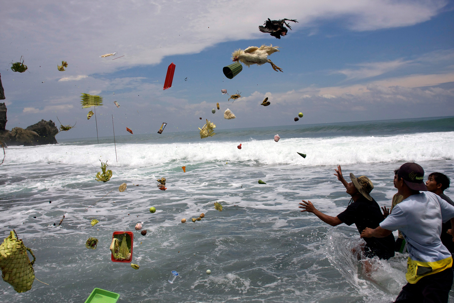 March 7, 2012. Indonesian men try to catch offerings thrown into the sea by Hindu worshippers during the ritual of Melasti on a beach in Gunung Kidul, Yogyakarta, Indonesia.