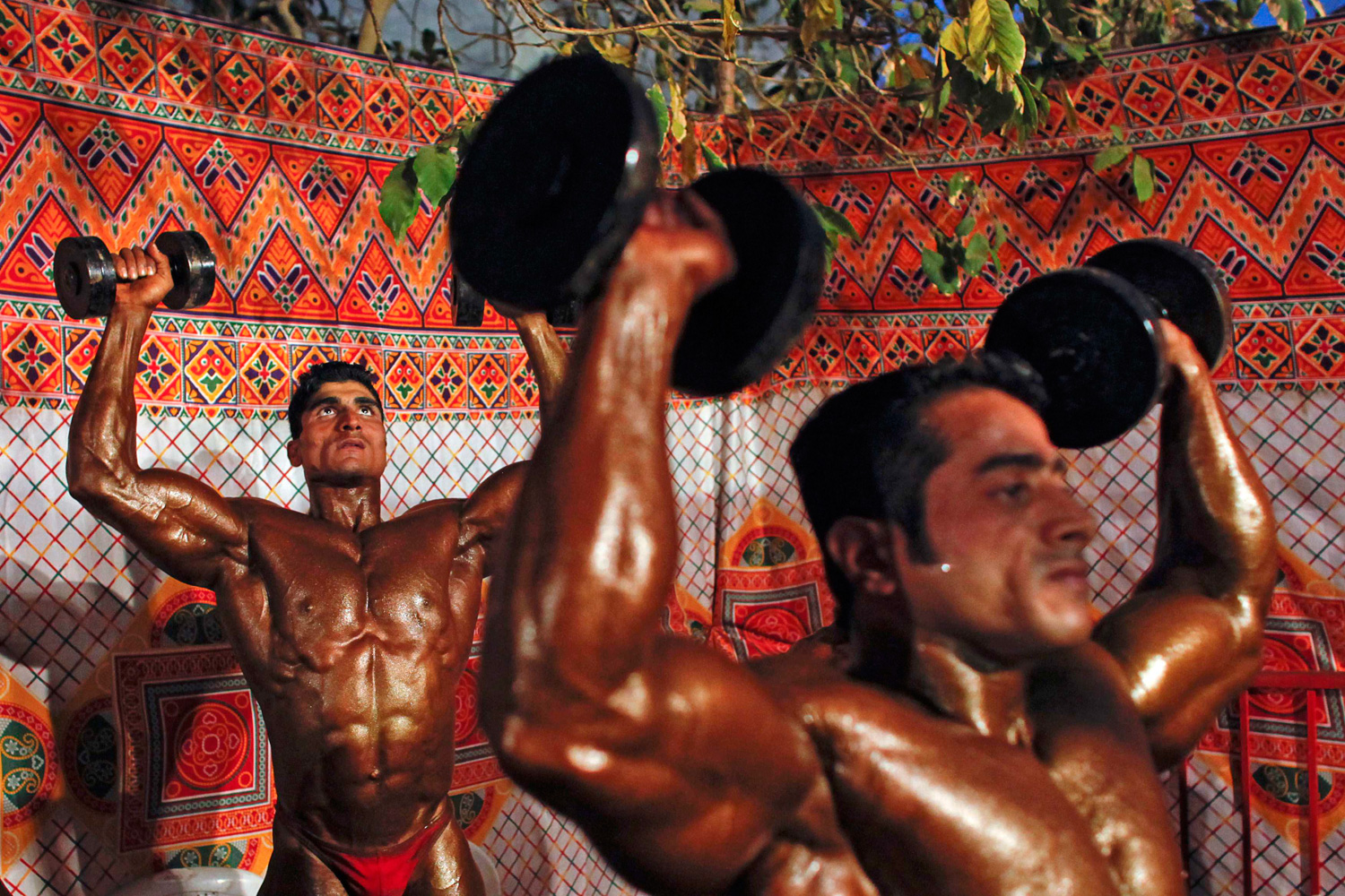 March 31, 2012. Competitors warm up backstage during a body building competition in Mumbai.