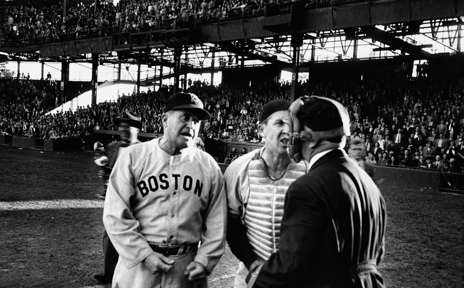 After umpire William Grieve issues a walk to a Washington pinch-hitter, Red Sox manager Joe McCarthy and catcher Birdie Tebbetts express their doubts about Grieve's judgment, 1949.
