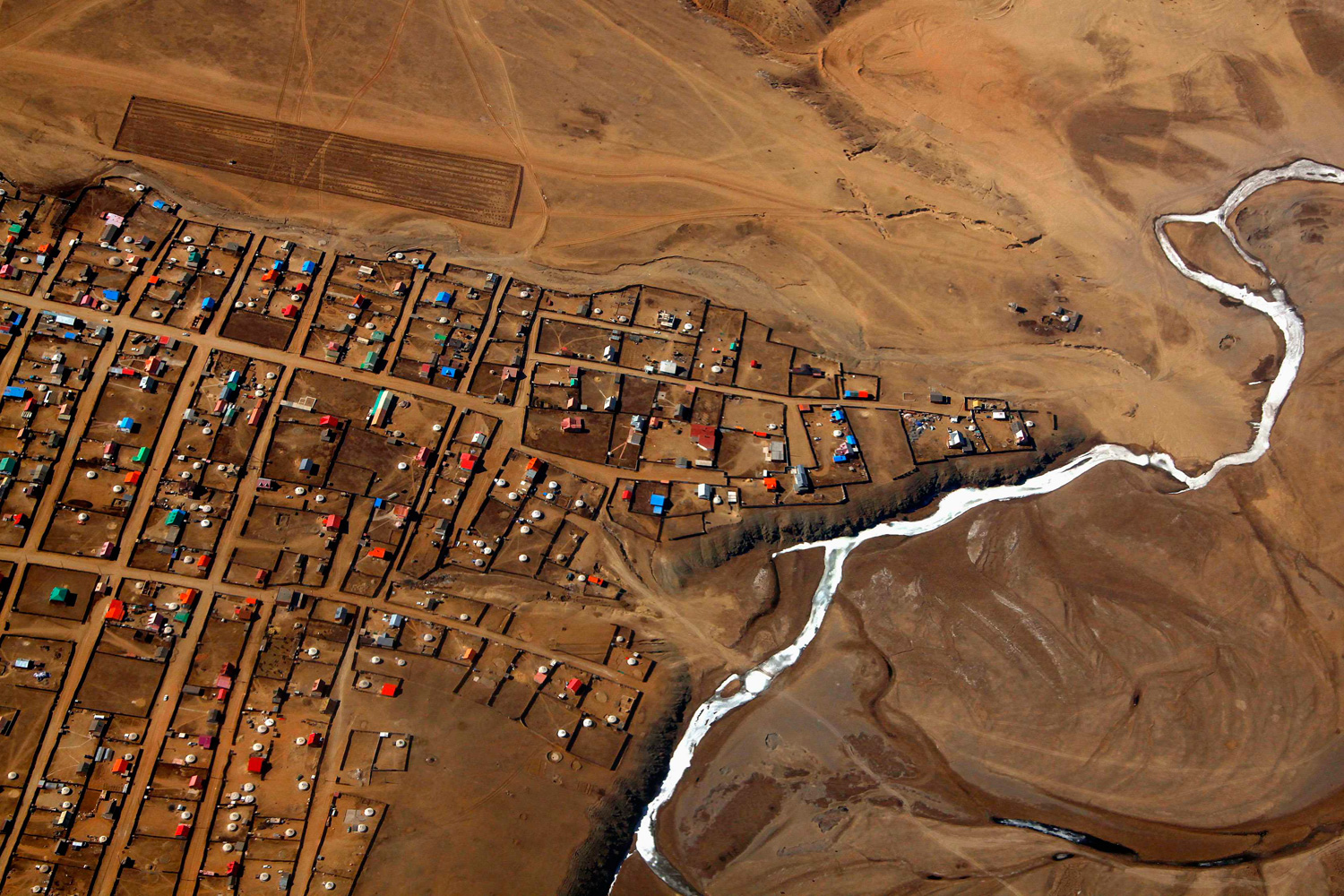 April 3, 2012. A frozen river is seen next to a group of houses located on the outskirts of the Mongolian capital city of Ulaanbaatar.