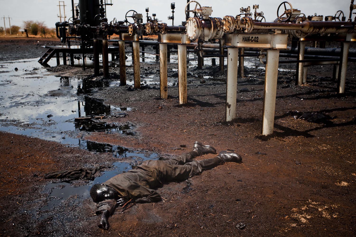 A soldier of the northern regime's army, the Sudan Armed Forces (SAF), lies dead, immersed in oil next to a leaking petroleum facility after heavy fighting with southern SPLA troops after they entered Heglig in mid April.