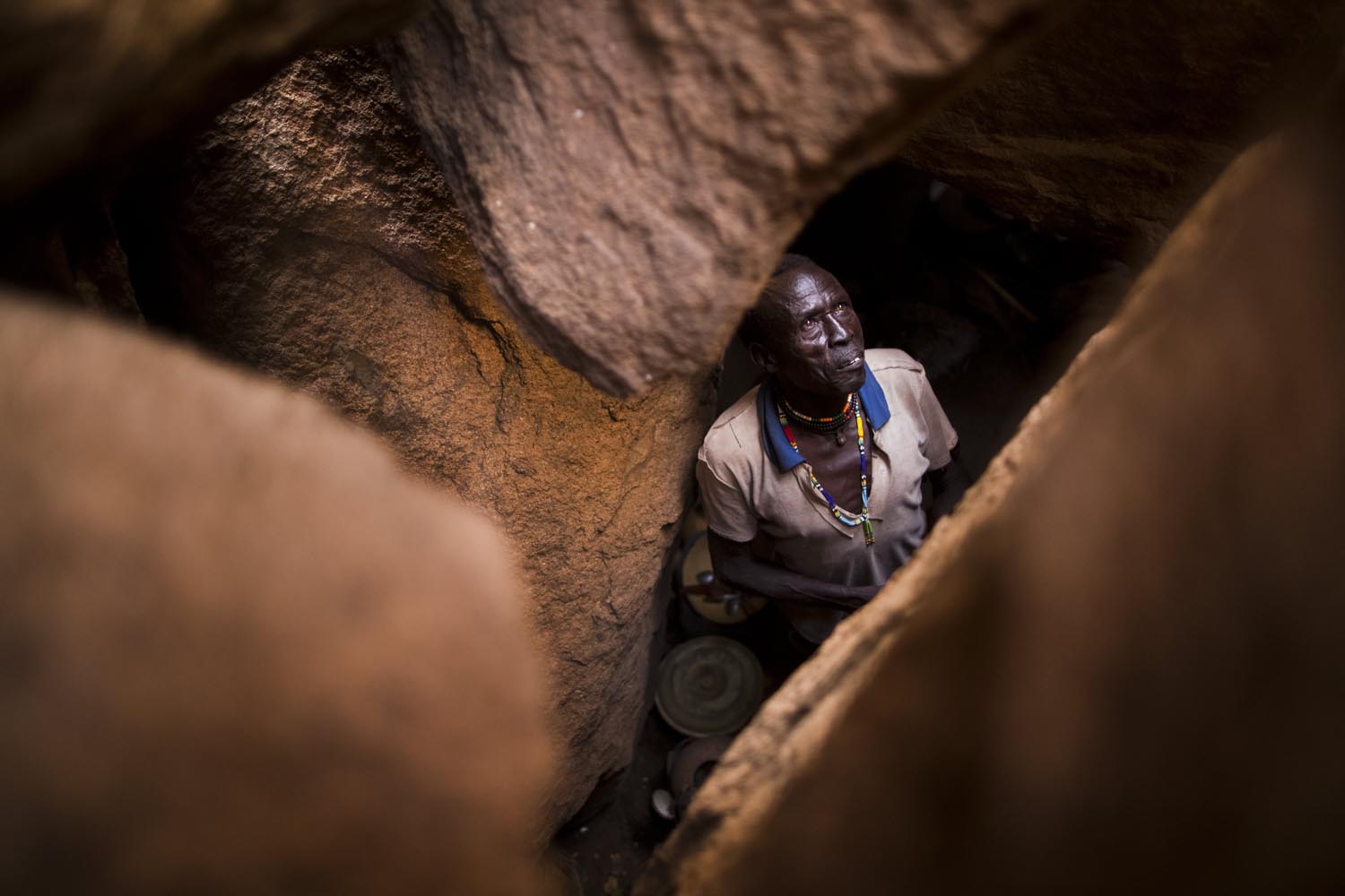 An older Nuban man looks up from his home in a cave after hiding for months from bombings by the SAF.