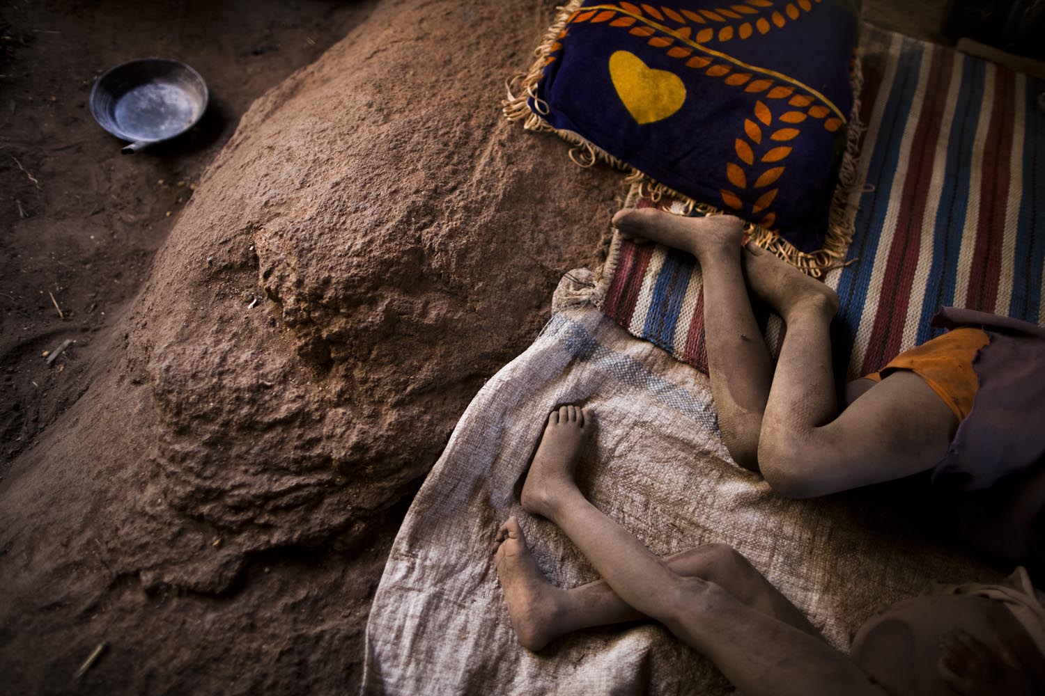 Two hungry Nuban children sleep on rocks inside caves where they have sought protection from north Sudan bombers.