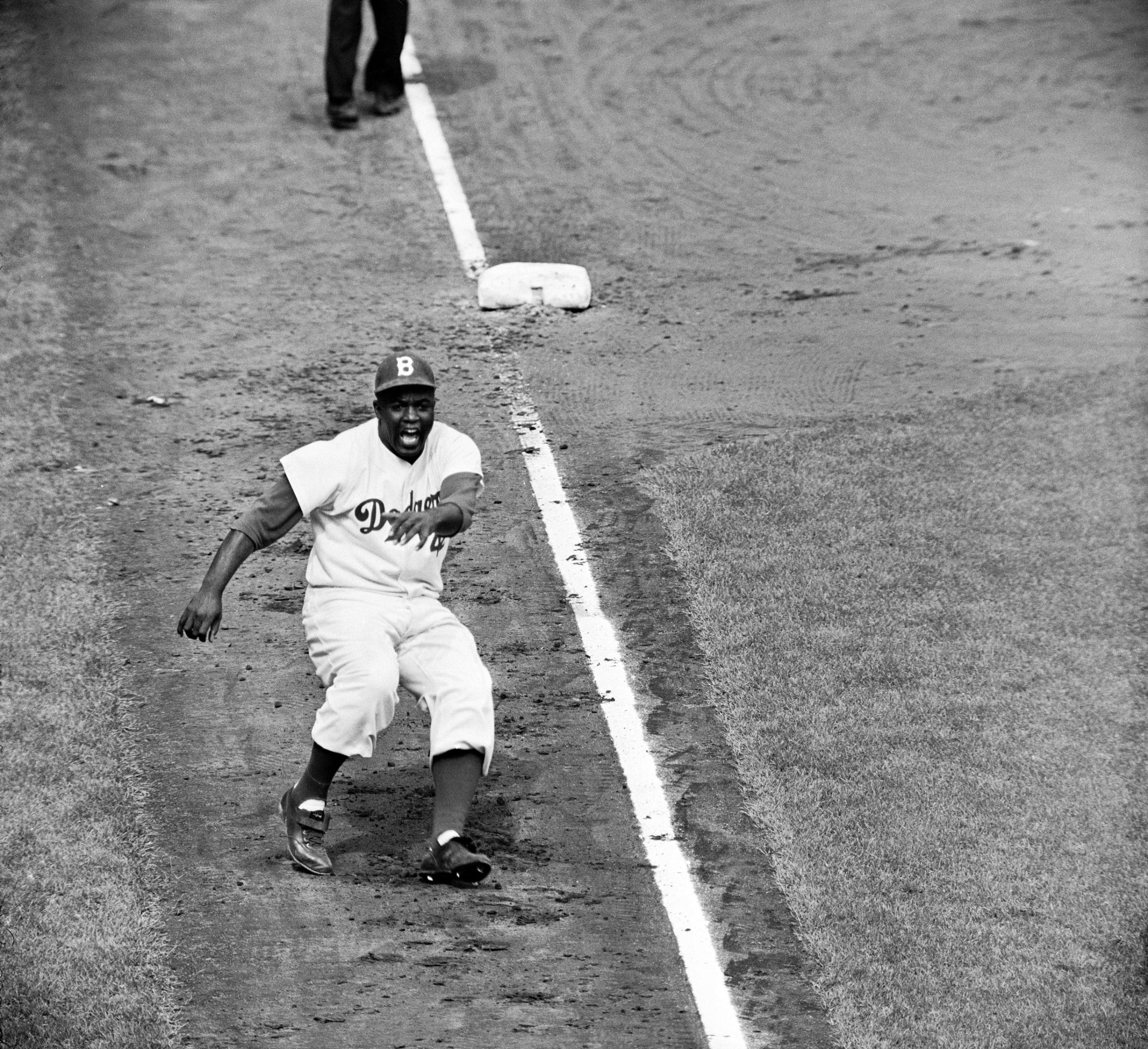 Hoping to distract Yankee catcher Yogi Berra and disrupt the pitcher, Bob Turley, Jackie Robinson dances off of third base during the third game of the 1955 World Series at Ebbets Field.