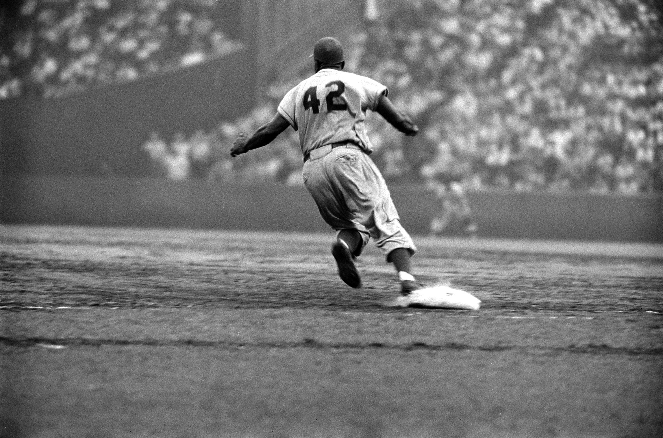 Jackie Robinson rounds first during a game against the Giants in 1956.