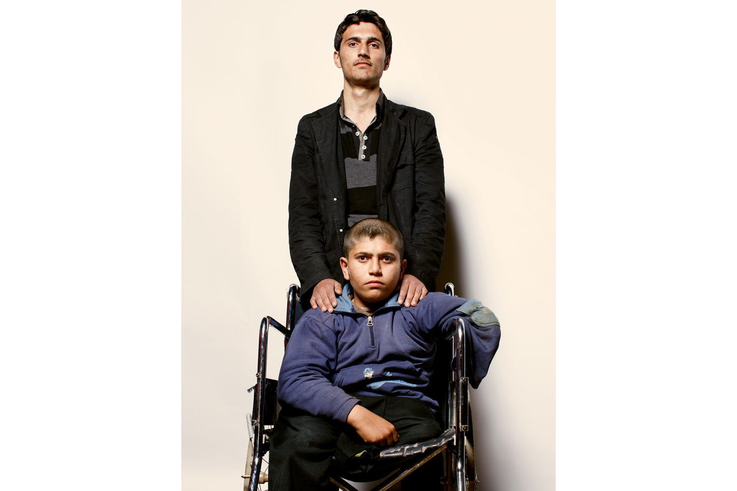 Ahmad (in wheelchair), 13, and his brother Abdullah, 20Ahmad:  I've had this chair for a while. It had to come with me. My brother carried me, and a good man carried my chair. Abdullah:  I could see that death was behind us, and in front of us, there was a faint hope of life. He drives me mad sometimes, and he's a handful, but he's my brother. I would not leave him. I carried him on my back for about four hours, from hill to hill.
