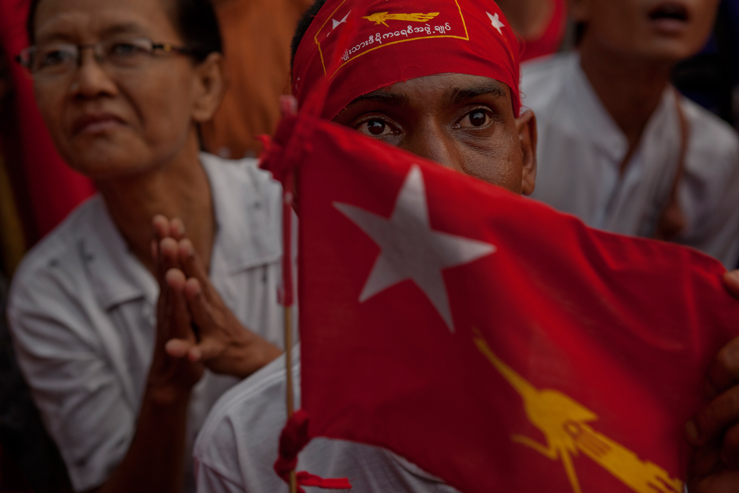 April 1, 2012. Waiting expectantly for the vote count at NLD headquarters, a supporter
                              holds a party flag, emblazoned with the party symbol of the  Fighting Peacock.