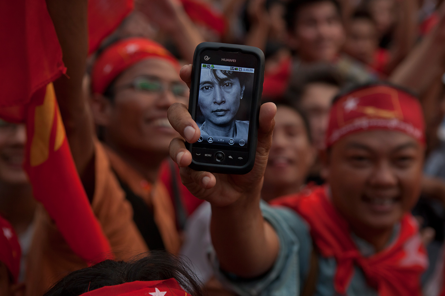 April 1, 2012. During the celebration, an NLD supporter holds up his mobile phone with a picture of Aung San Suu Kyi, who is respectfully and affectionately known as  The Lady  to the Burmese population.