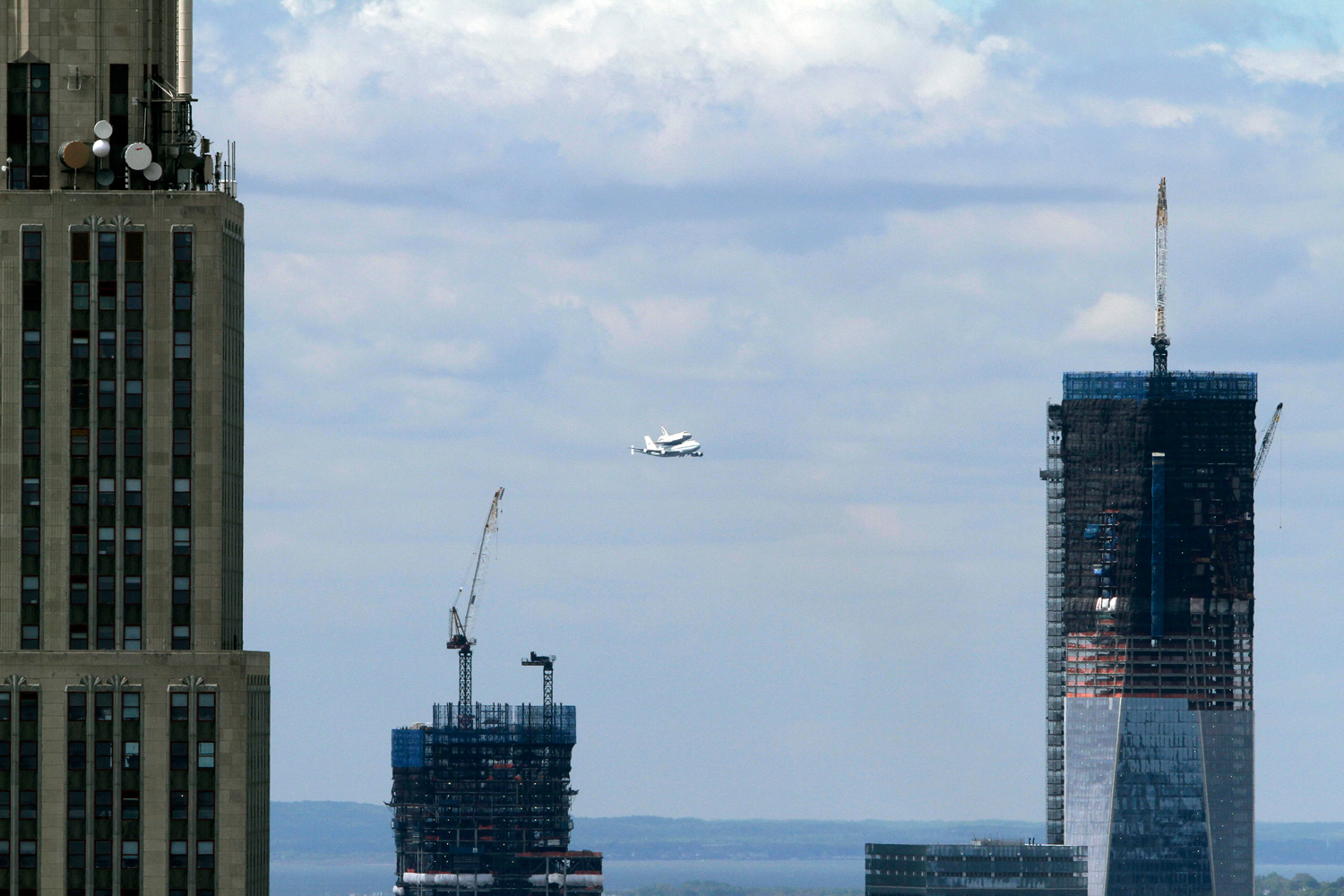 April 27, 2012. The Space Shuttle Enterprise, riding on the back of the NASA 747 Shuttle Carrier Aircraft, flies between the Empire State Building, left, and One World Trade Center as it arrives in New York City.