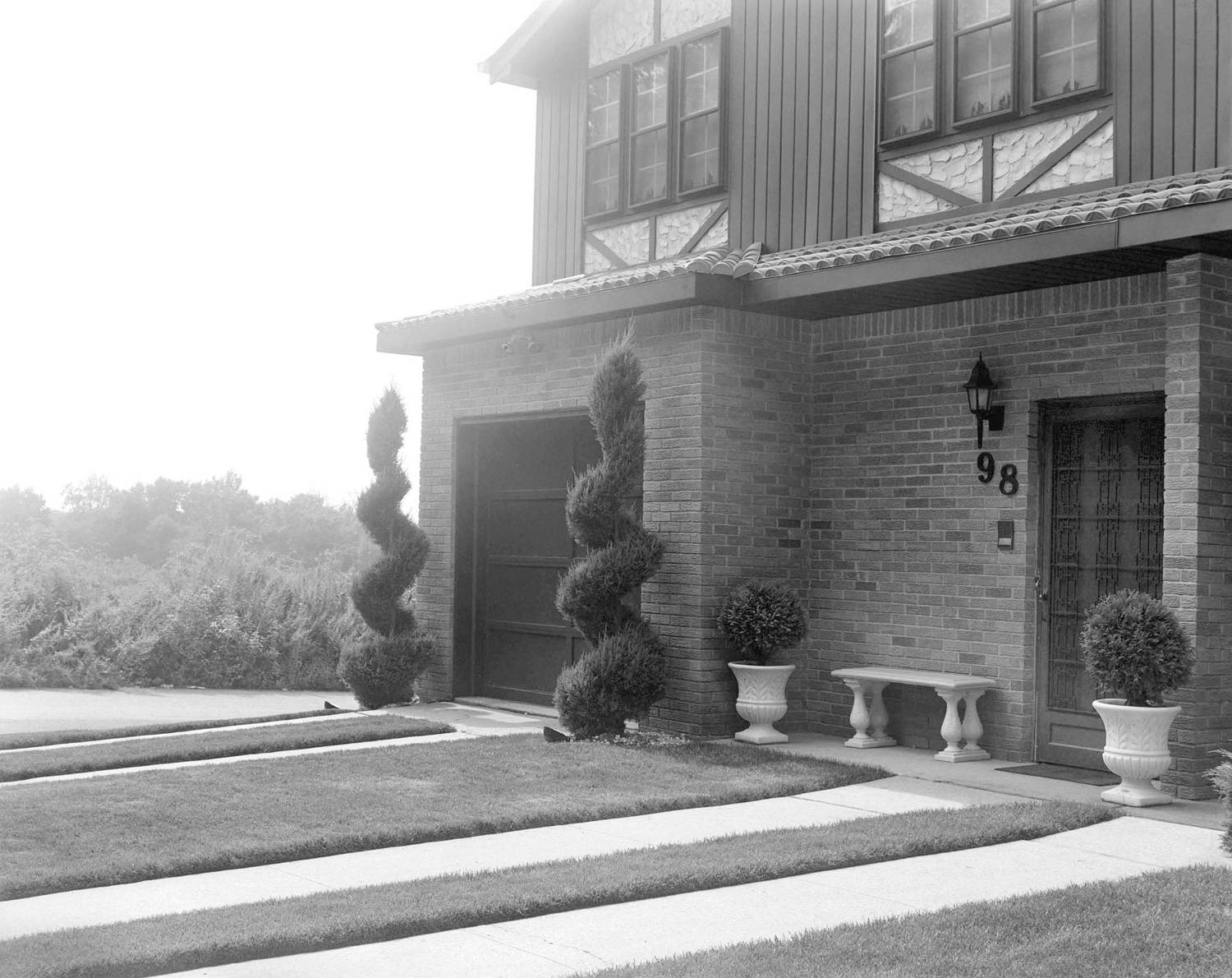 House with spiral bushes bordering the entrance to the garage.