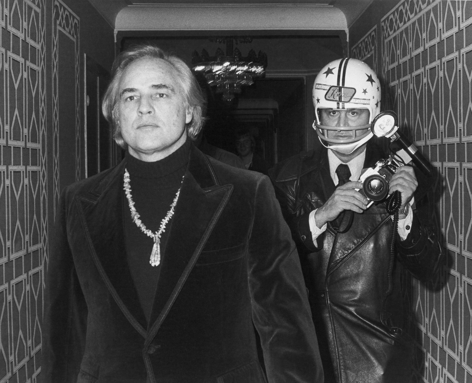 Marlon Brando and Ron Galella wearing a football helmet at the Waldorf Astoria Hotel. Nov. 26, 1974