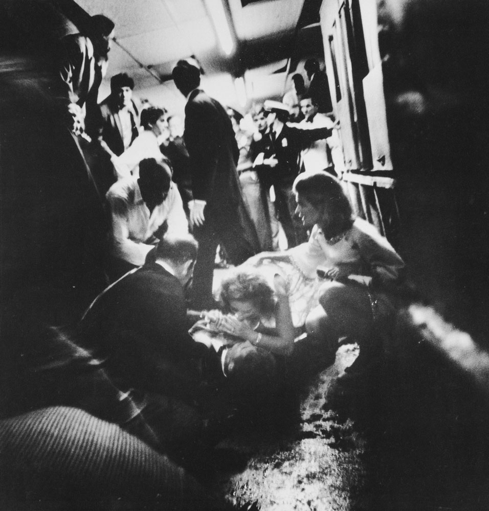Mrs. Robert Kennedy, who had been walking with the senator, crouched over her dying husband, whispering to him as he lay on the floor. Beside her, waiting for the ambulance attendants to arrive, knelt her sister-in-law, Mrs. Stephen Smith and Dr. Ross Miller.