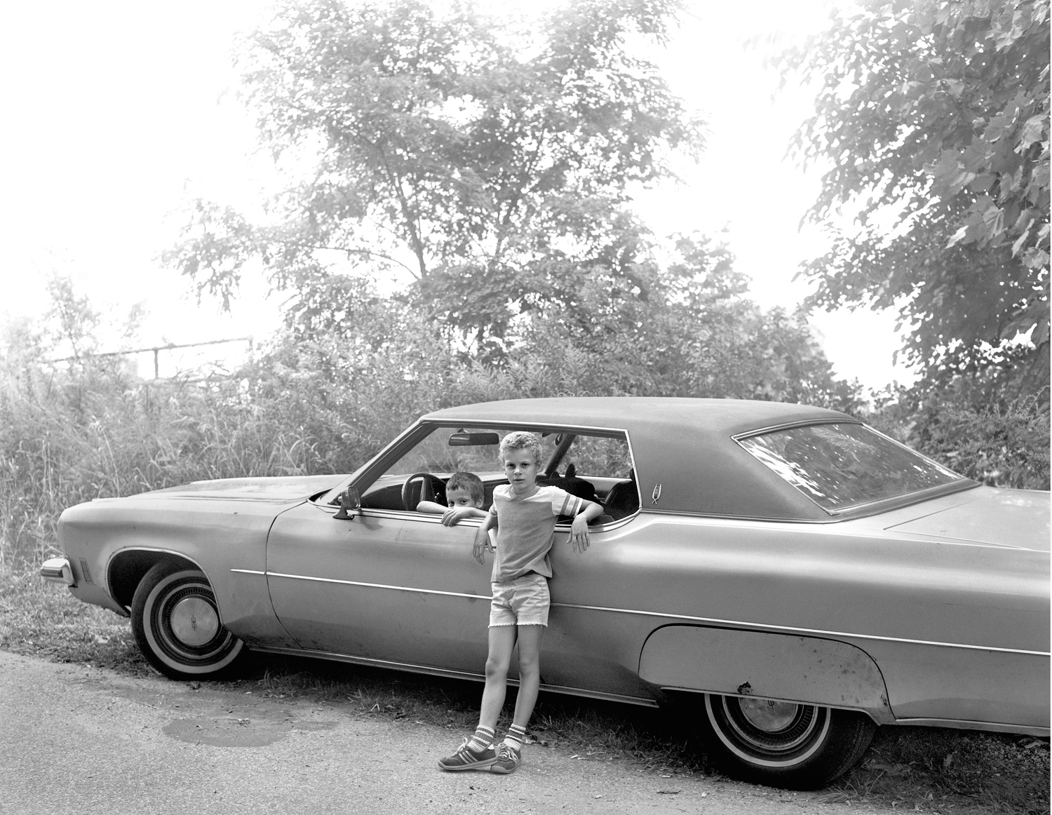 Two boys pose with a car.