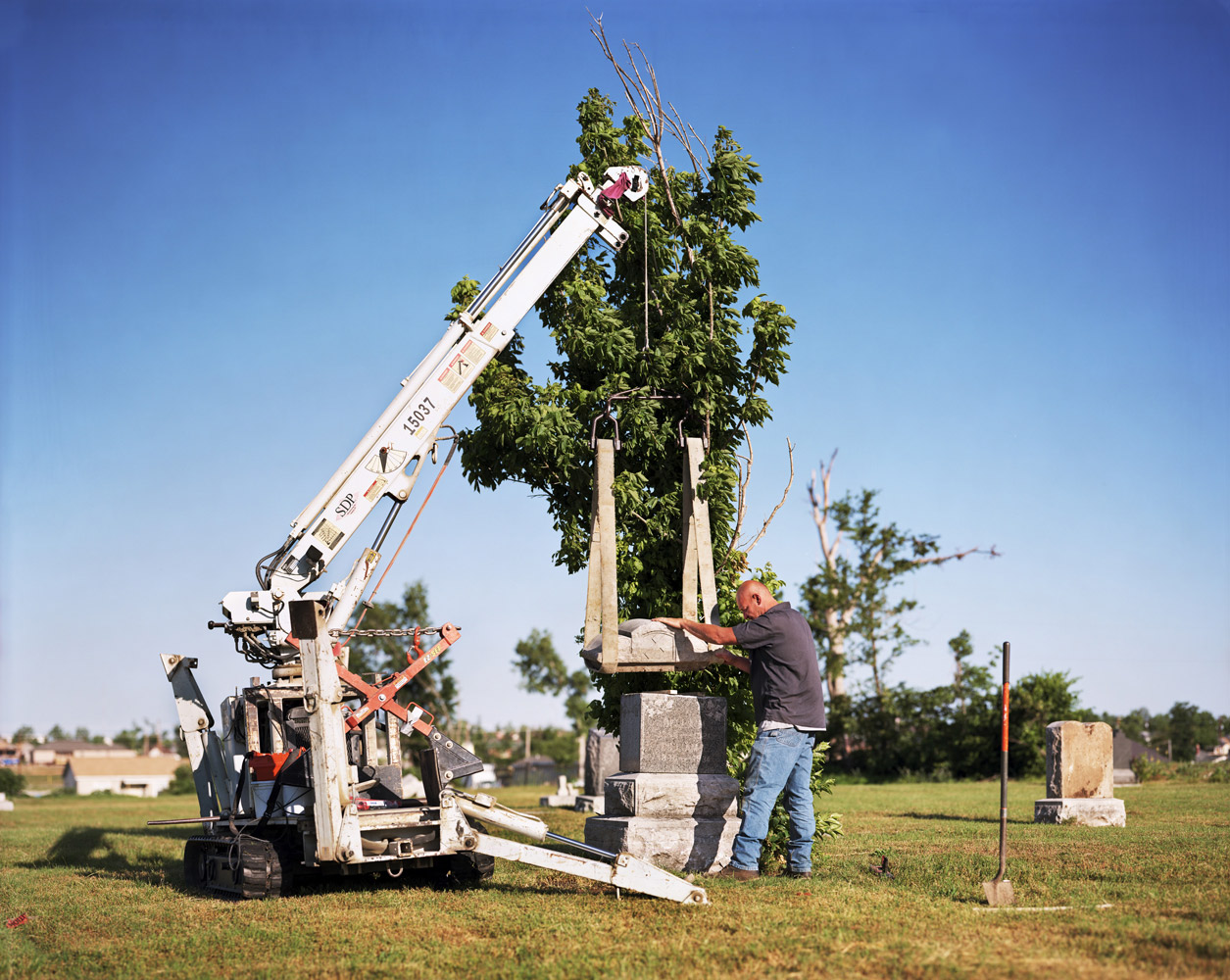 Tony Housley repairs a fallen gravestone in a Joplin cemetery.