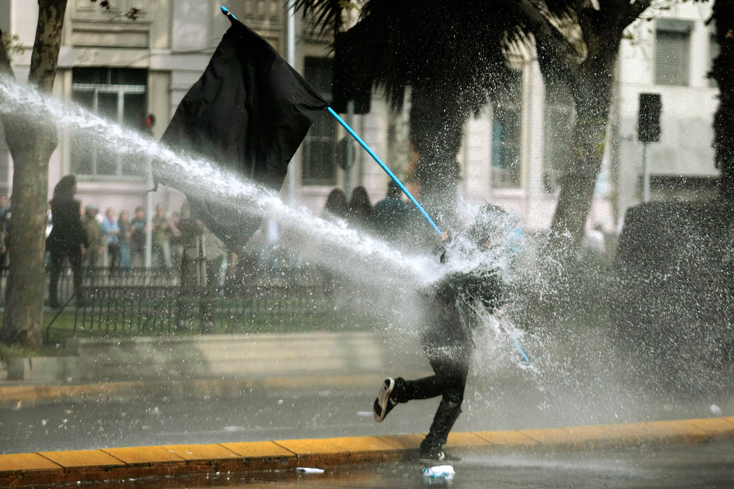 May 1, 2012. A protester gets sprayed by a water canon during a May Day march in Santiago, Chile. Clashes with security forces and riots marred the rally to mark International Labor Day.