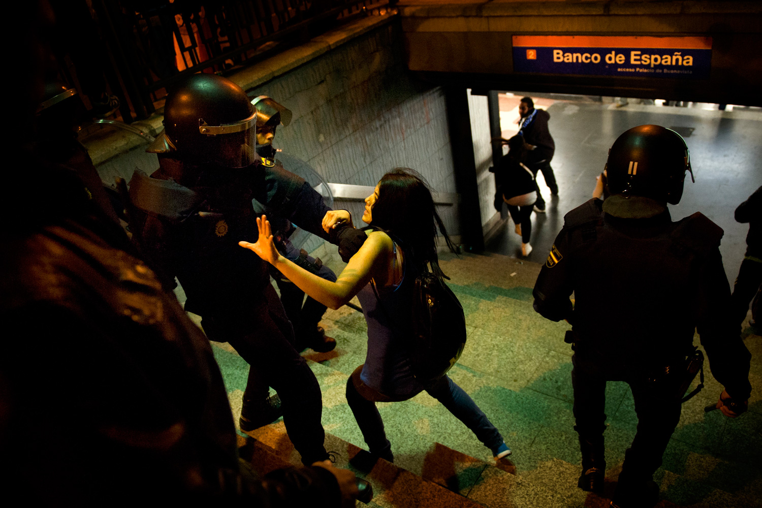 May 3, 2012. A police officer in riot gear raises his baton before hitting a girl during a celebration after Real Madrid won the Spanish Soccer La Liga, at a metro station in Madrid.