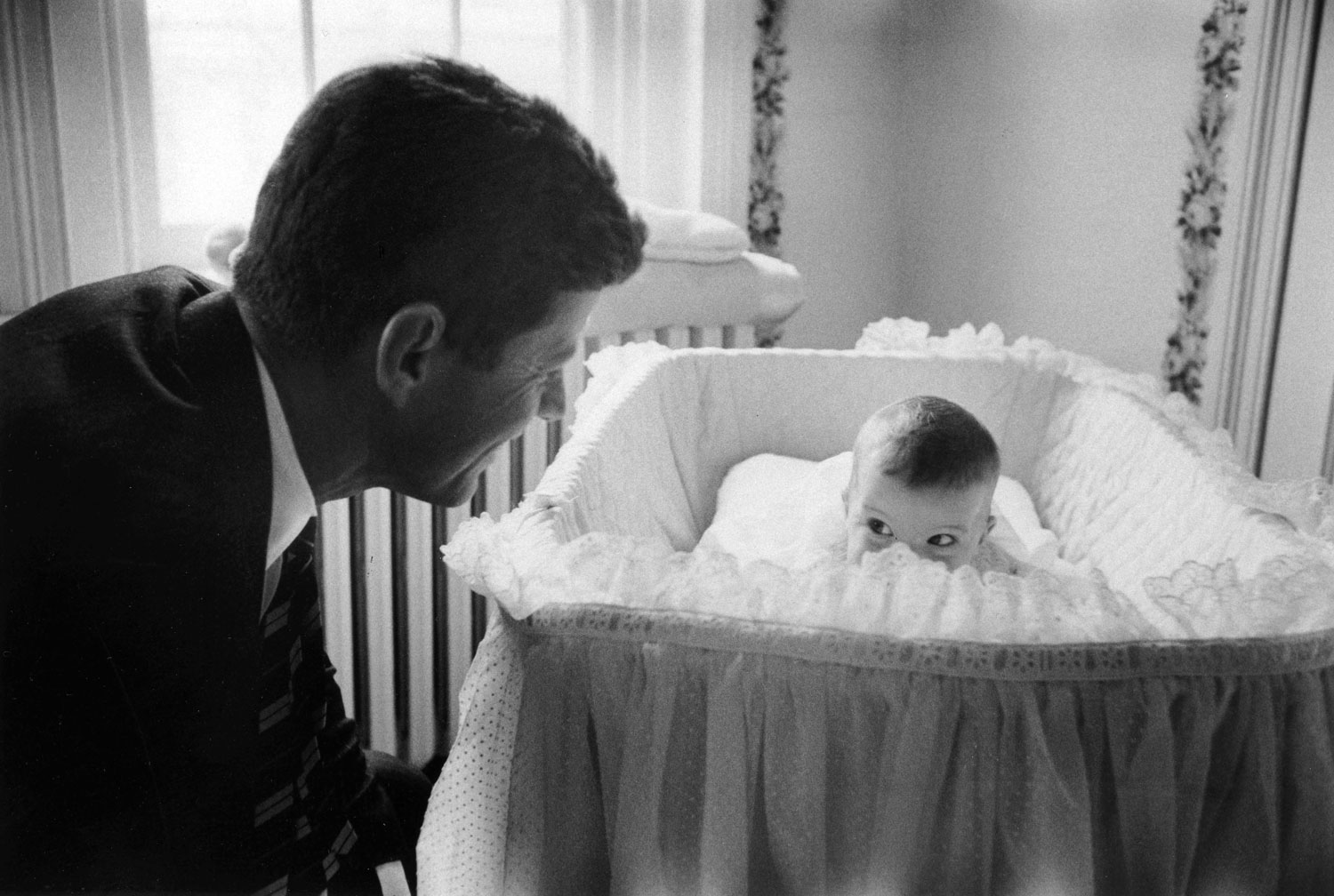 Senator John F. Kennedy plays peek-a-boo with daughter Caroline in 1958.
