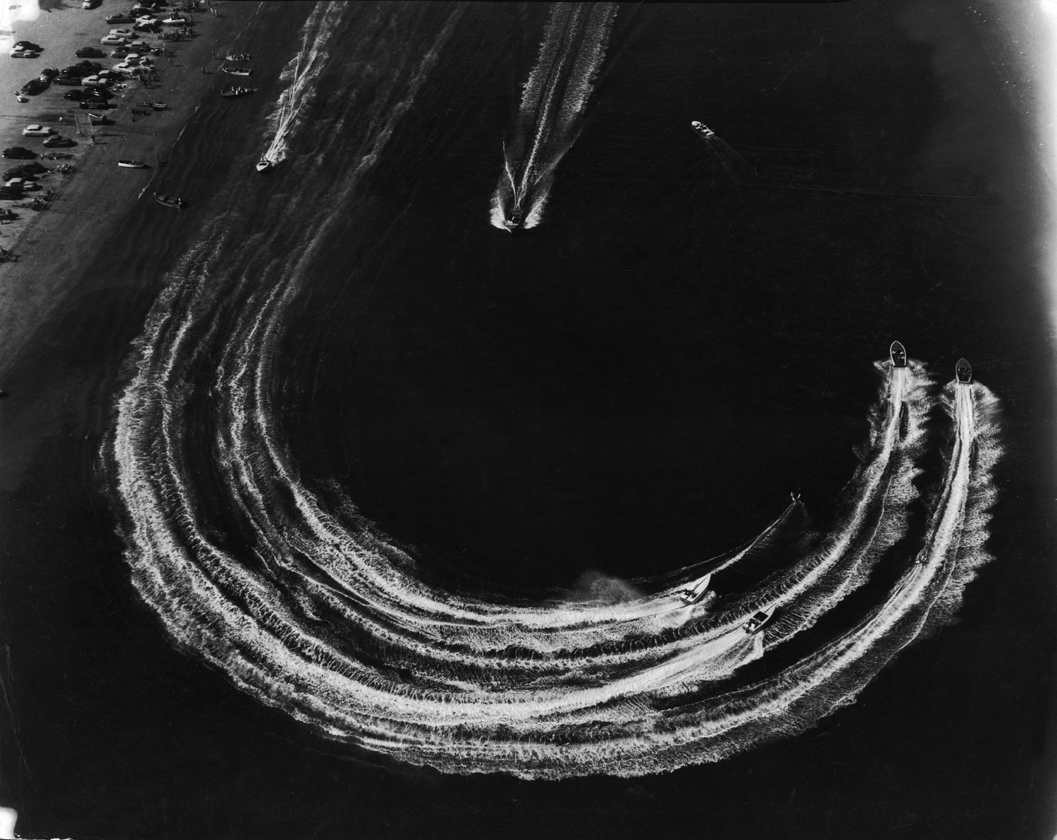 Water skiers and motorboats speed across the water, Long Beach, Calif., photographed from a helicopter, 1952.