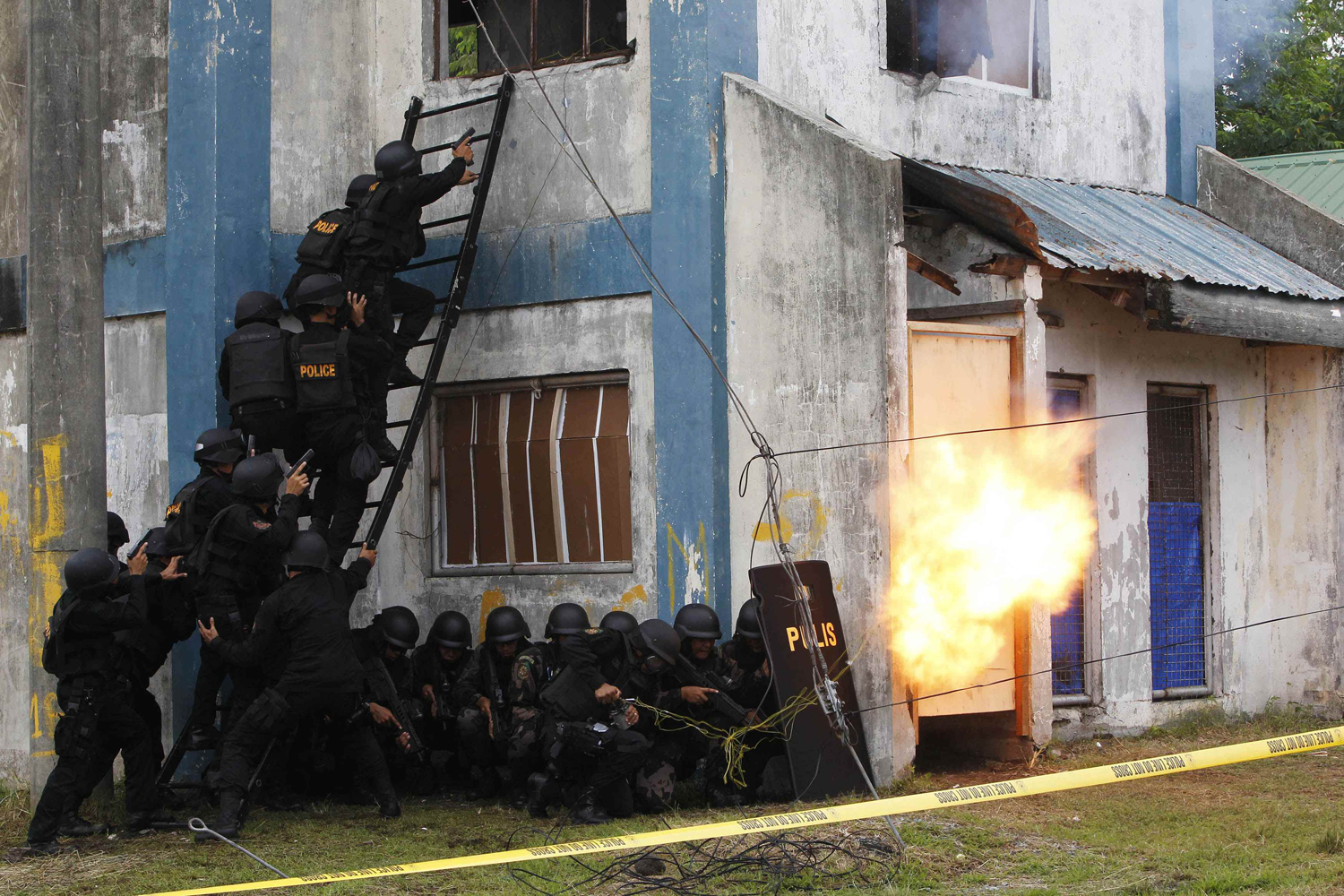 June 1, 2012. Members of the Philippine National Police Aviation Security Group use an improvised bomb to blast through the main door of a building, simulating an airport control tower seized by a mock terrorist group, at Taguig city, south of Manila.