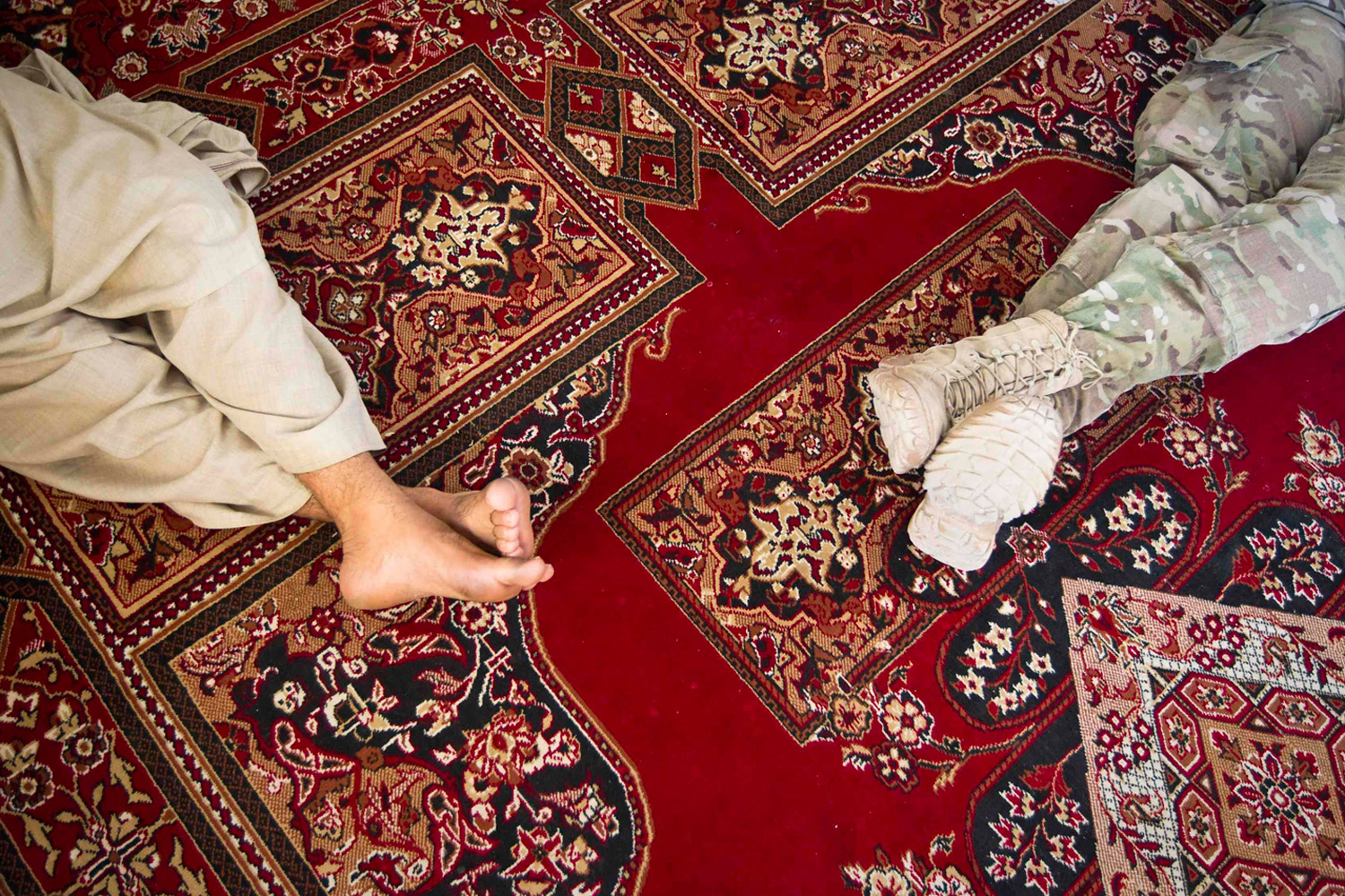 June 1, 2012. Michael Kelvington (R), a U.S. Army Captain, commander of the Battle company, 1-508 Parachute Infantry battalion, 4th Brigade Combat Team, 82nd Airborne Division, and Haji Lala, a local elder, sit on a carpet as they share dinner in the town of Senjaray, Afghanistan.
