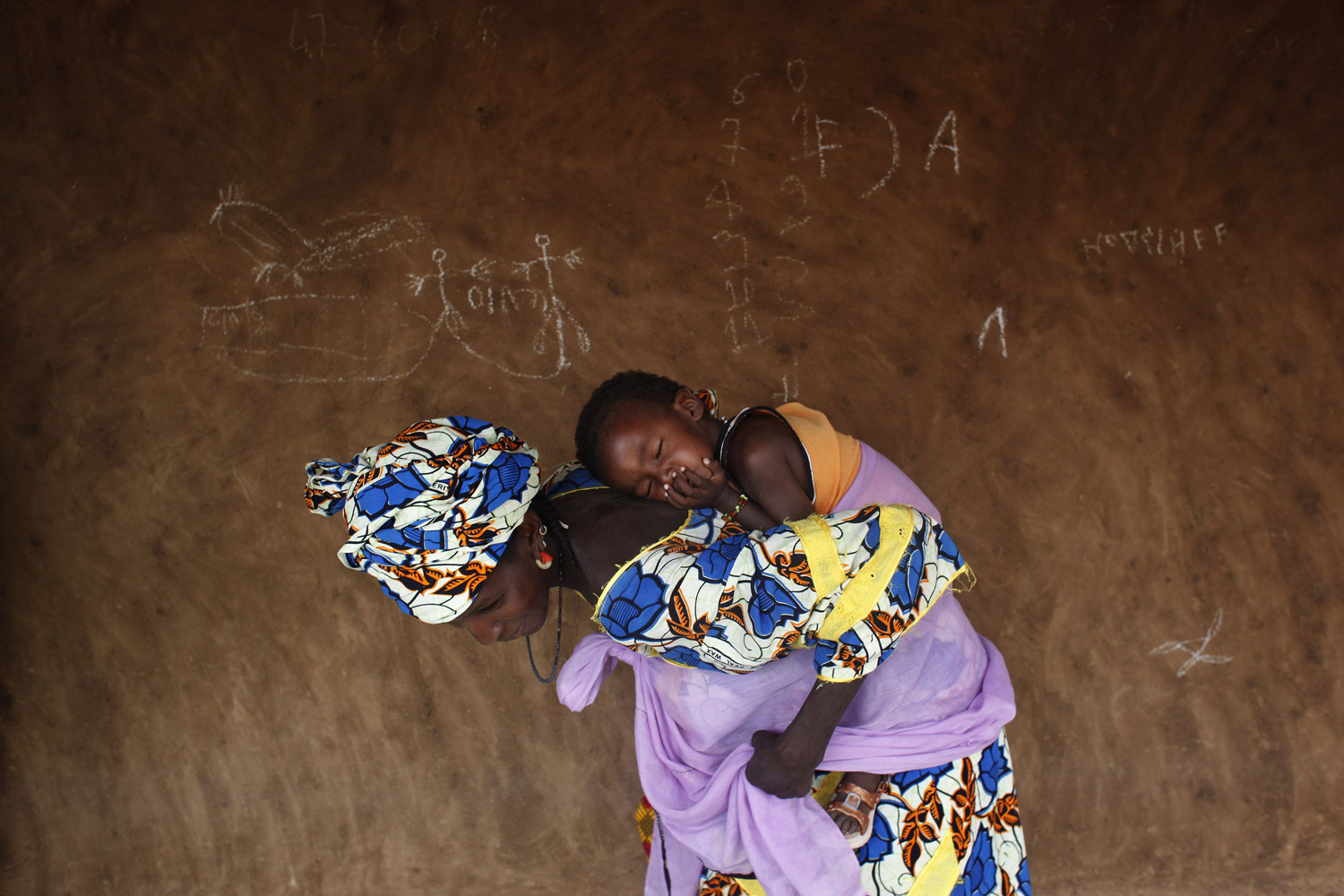 June 3, 2012. A woman wraps her sleeping baby on her back after a talk with members of the Spanish NGO Accion Contra el Hambre (Action Against Hunger) about good sanitation and hygiene practices in Niomel, Mauritania.