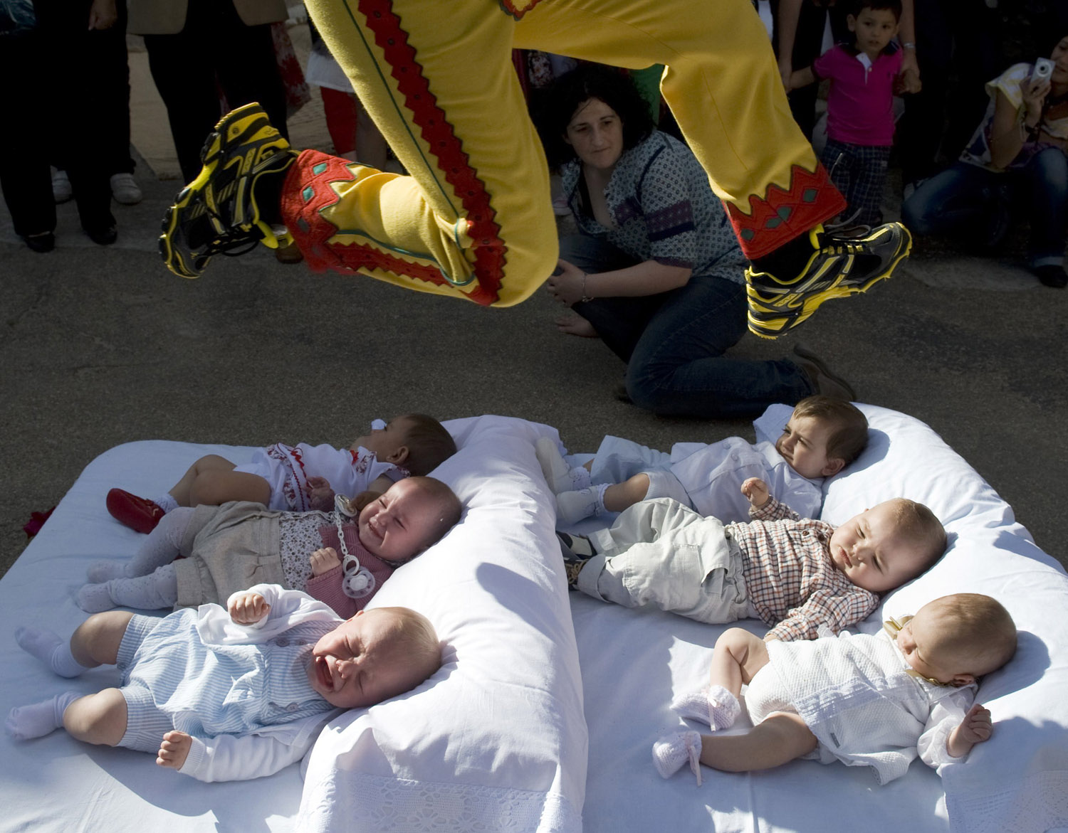 Man dressed in a red and yellow costume representing the devil, known as El Colacho, jumps over babies placed on a mattress during traditional Corpus Christi celebrations in Castrillo de Murcia, near Burgos, northern Spain