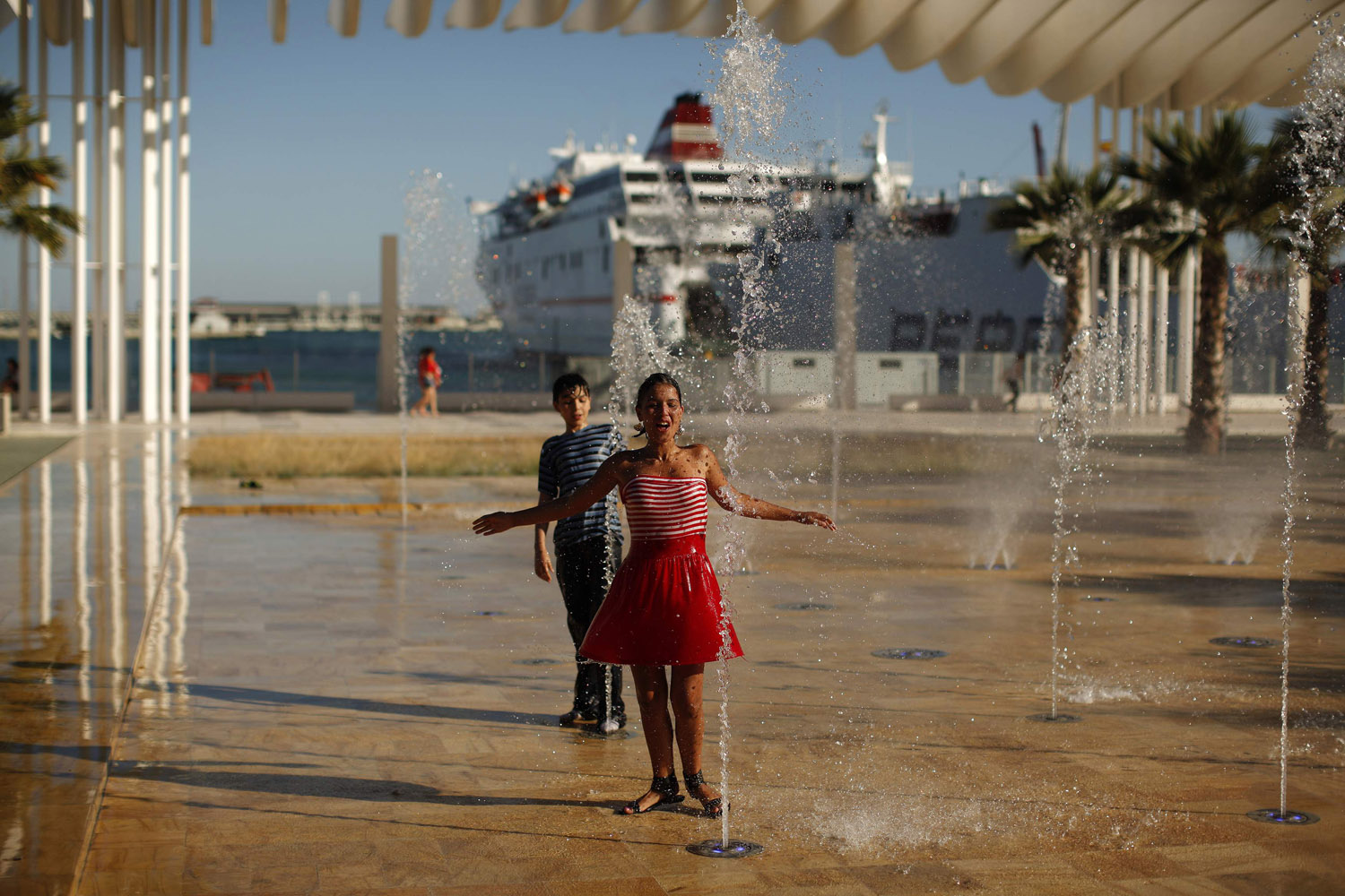 June 10, 2012. A girl and a boy cool off in a fountain during a hot day at the port in Malaga, southern Spain.