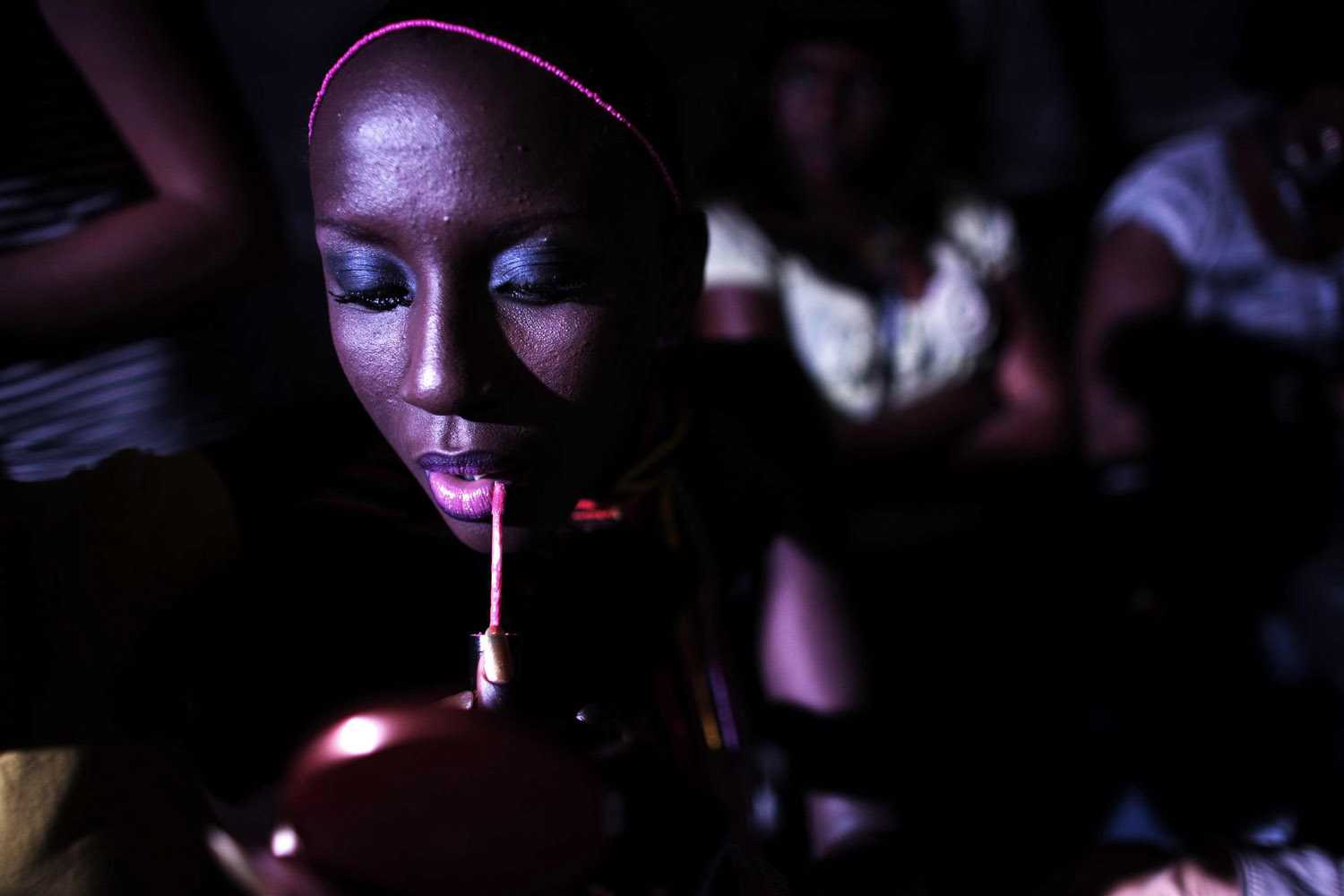 A model puts on make-up backstage during the 10th anniversary of Dakar Fashion Week