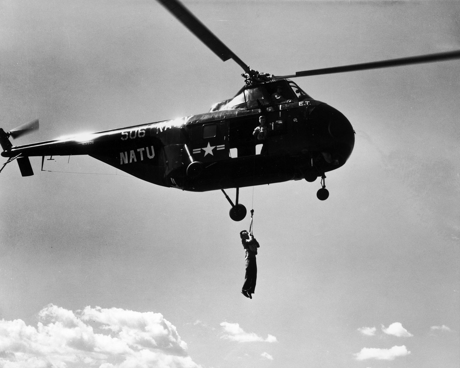 Margaret Bourke-White hangs from Navy helicopter to photograph rescue work.