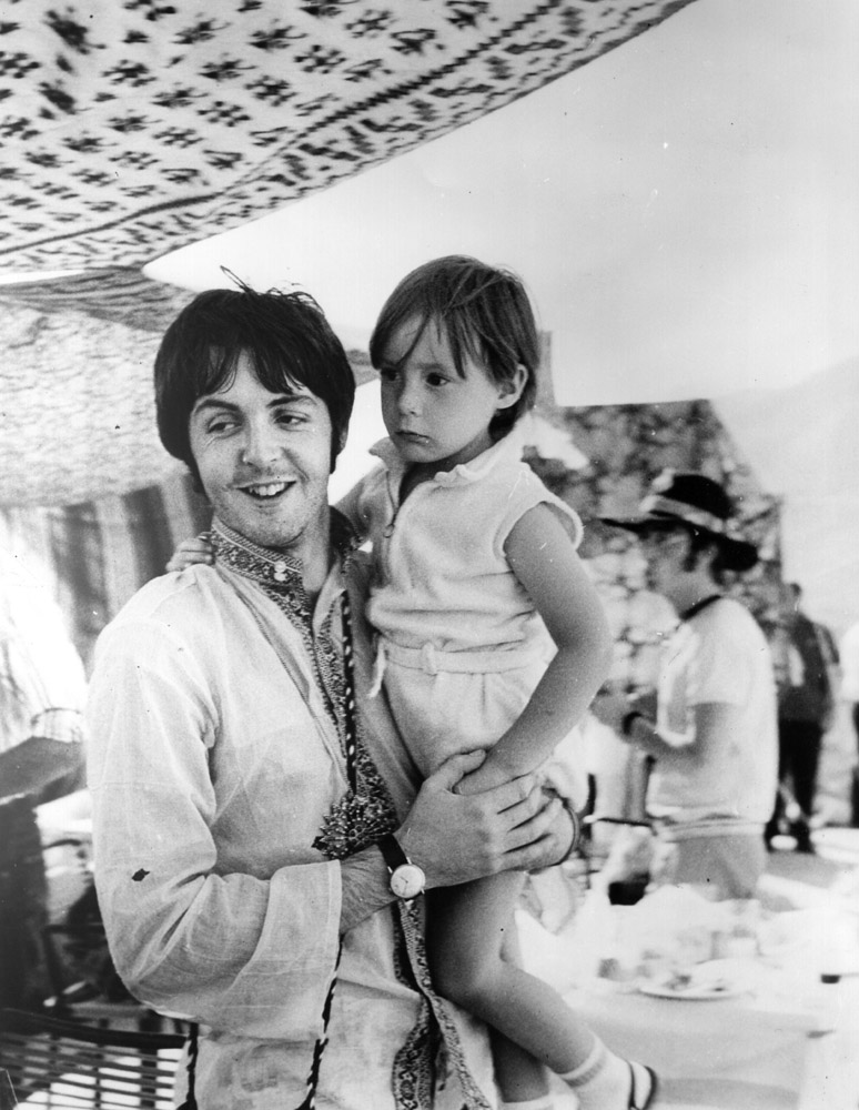 Beatles singer and bass player Paul McCartney holds four year old Julian, son of his colleague John Lennon (visible in the background) during a holiday near Athens in Greece.