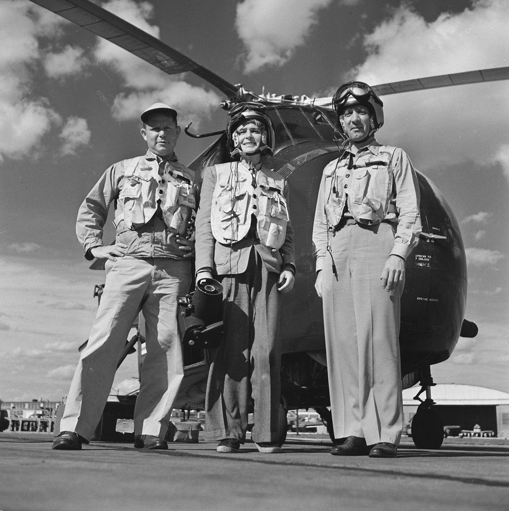 Margaret Bourke-White stands before a helicopter with two unidentified men, 195