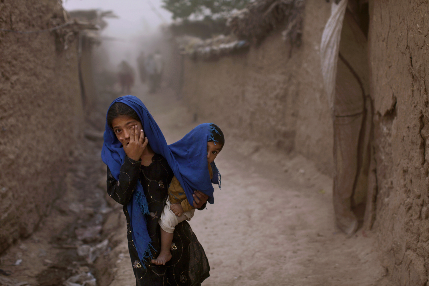 June 5, 2012. An Afghan refugee and her brother get caught in a sandstorm in a slum on the outskirts of Islamabad.