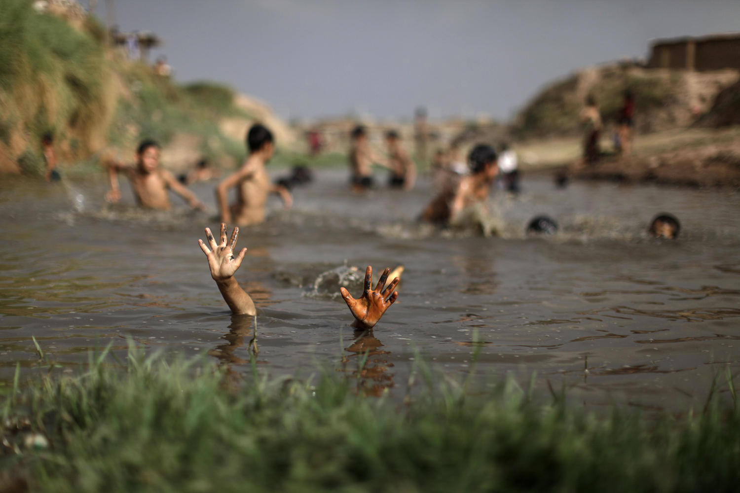 June 5, 2012. An Afghan refugee soaks in a polluted a stream to beat the heat on World Environment Day, in a slum area on the outskirts of Islamabad.