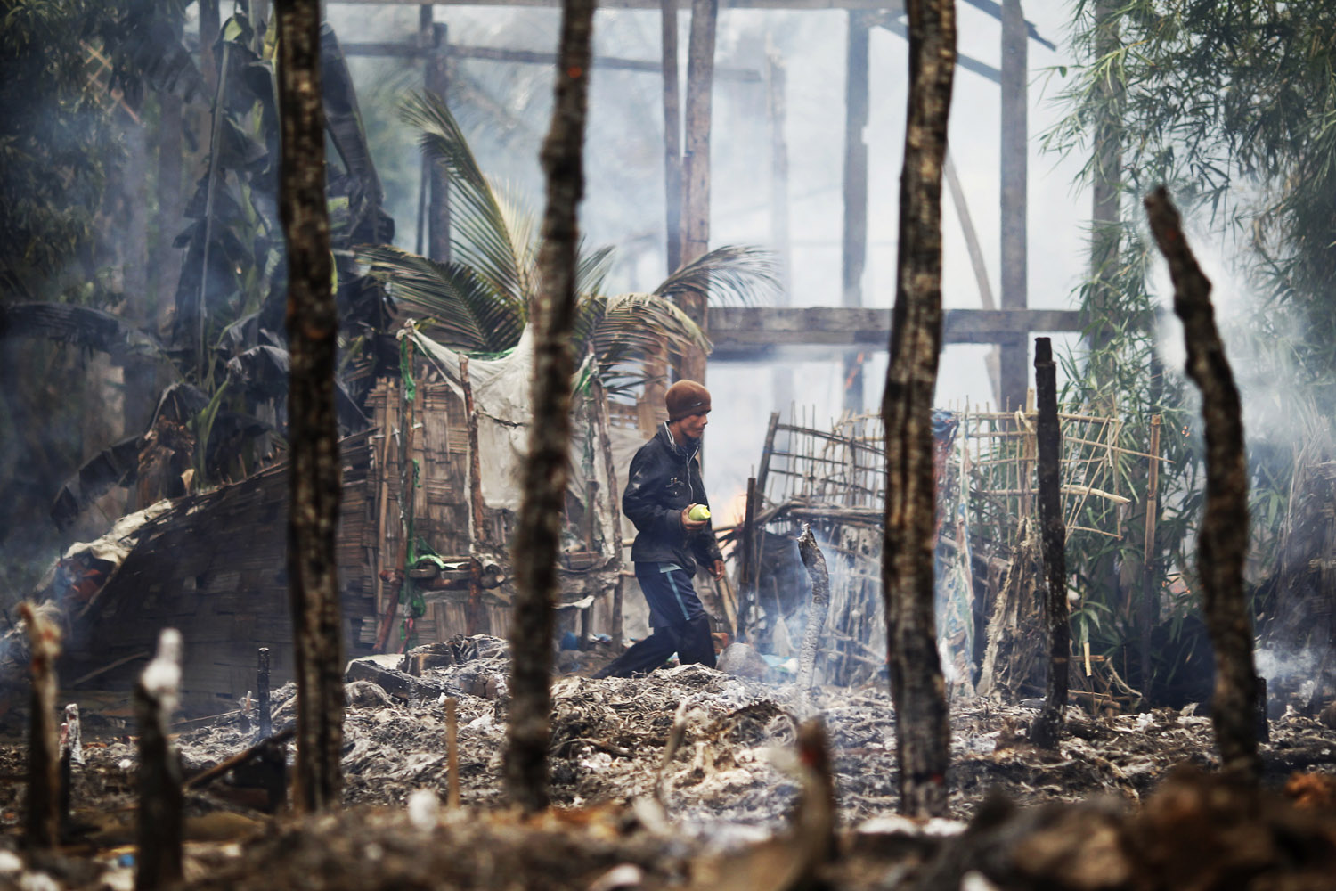 June 10, 2012. A man walks though a burnt Rohingya village during fighting between Buddhist Rakhine and Muslim Rohingya communities in Sittwe.