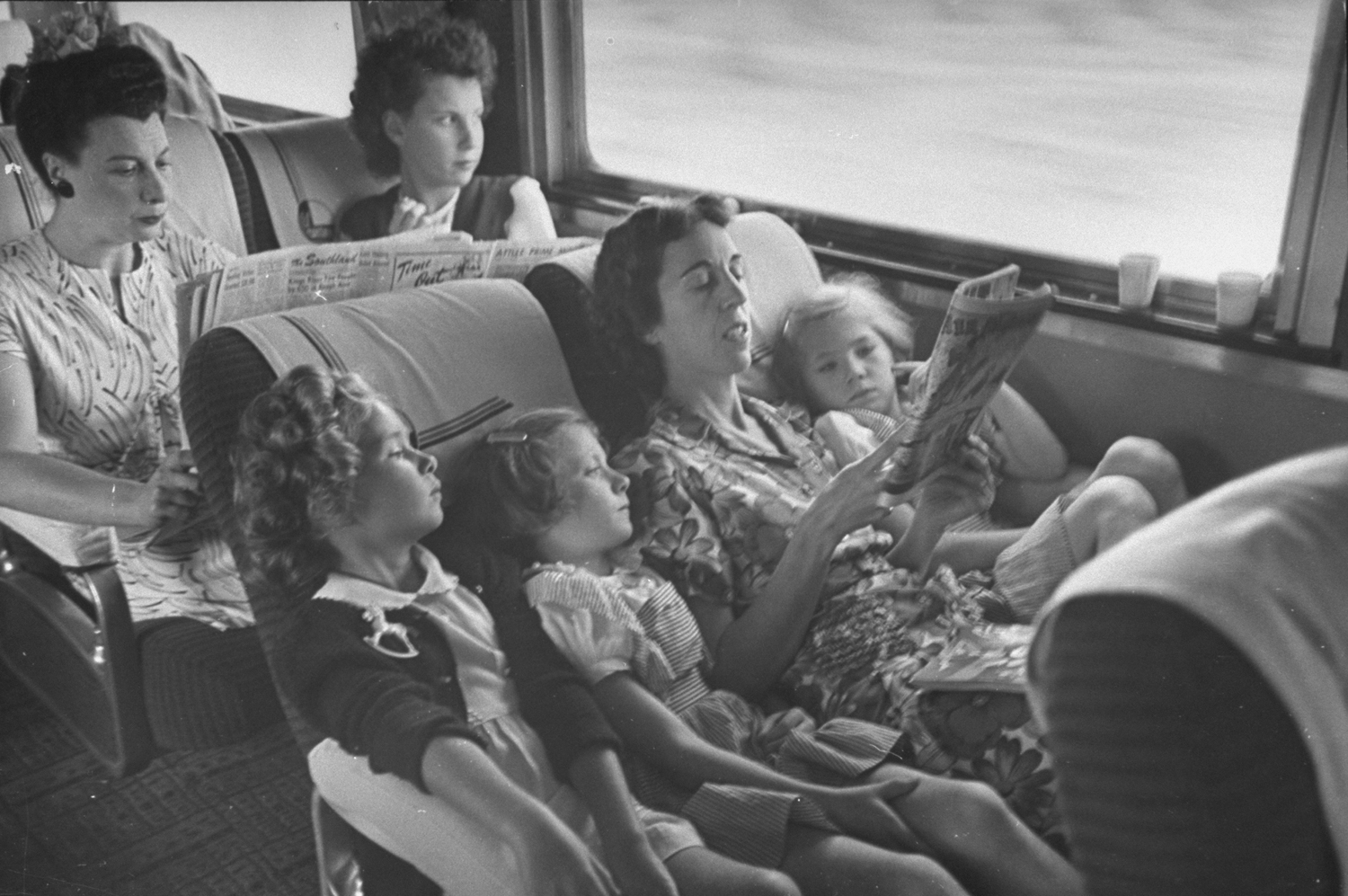 A mother reads her children the comics while traveling on the "El Capitan" train between Chicago and Los Angeles, 1945.