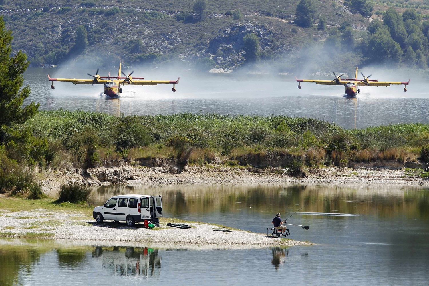 July 13, 2012. Firefighting planes fetch water from the Beniares reservoir to fight a wildfire next to the Sierra Mariola Nature Park in Cocentaina, Spain.