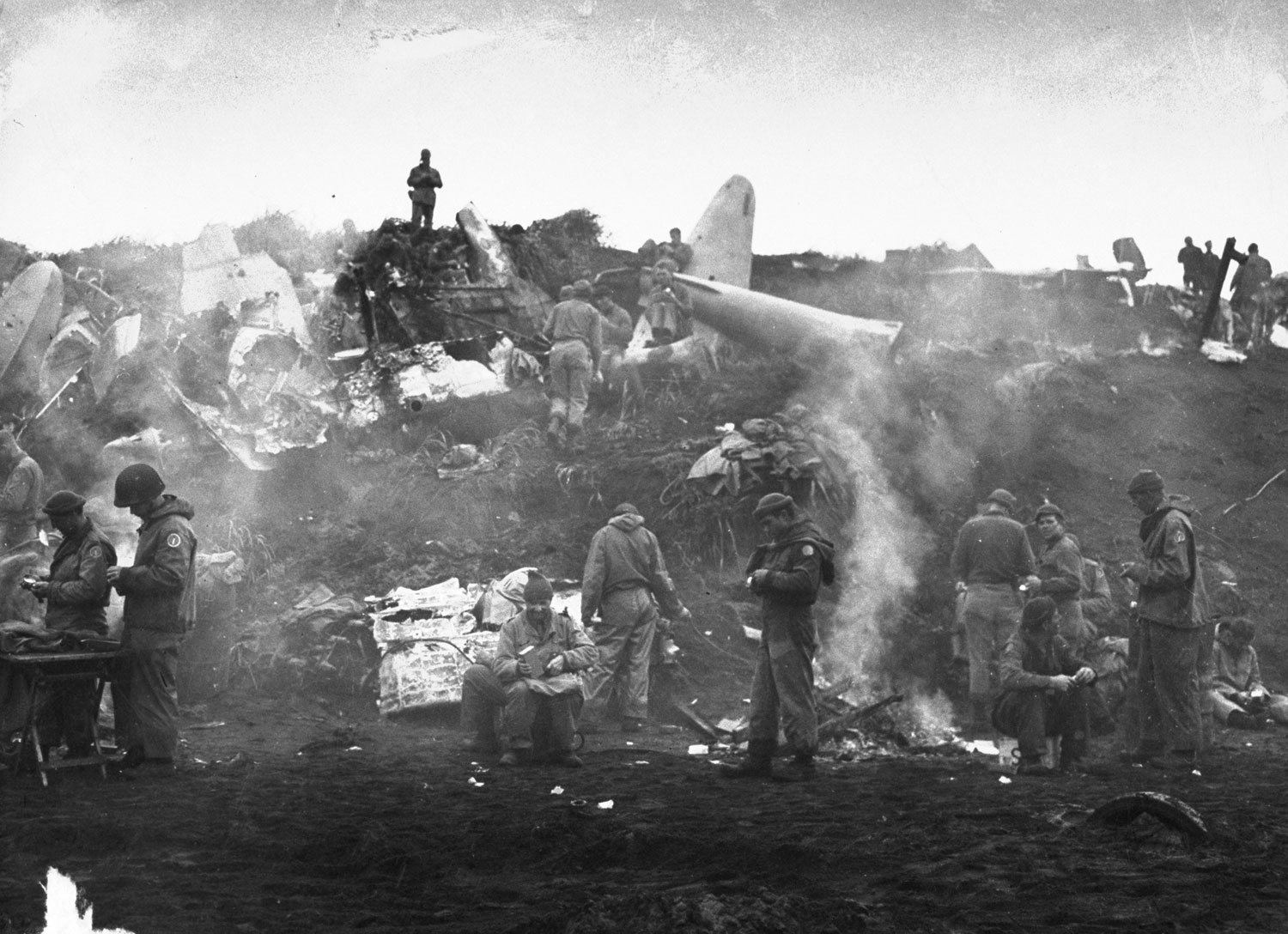 On the island of Kiska, men build fires near wrecked equipment and cook their meals, Alaska, 1943.