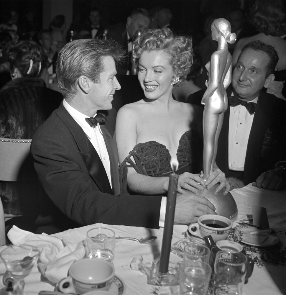 Marilyn Monroe, with actor Richard Basehart (left), holds her Henrietta Award during ceremony at the Club Del Mar, Santa Monica, Calif., 1952.