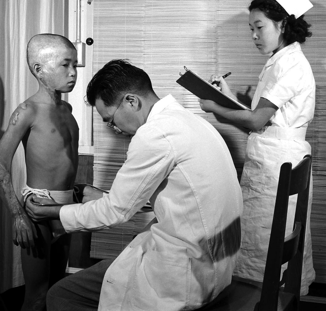 A boy badly burned by the Hiroshima bomb four years earlier is checked by a pediatrician in 1949.