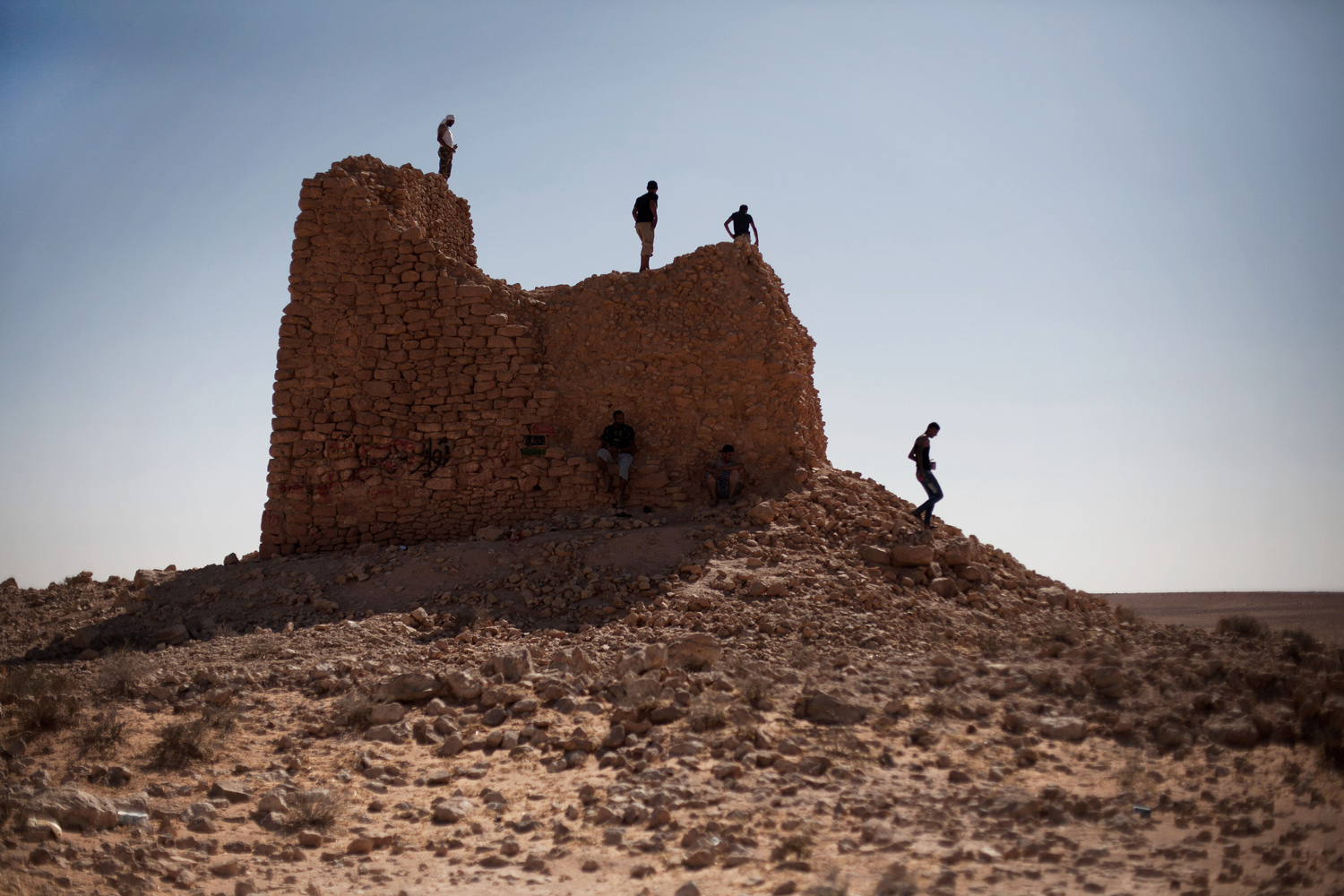 July 14, 2012. Libyan militia men scan the desert at the top of an old Italian defense tower during a patrol in the Bir Doufan area, on the border between Misrata and Bani Walid, Libya.