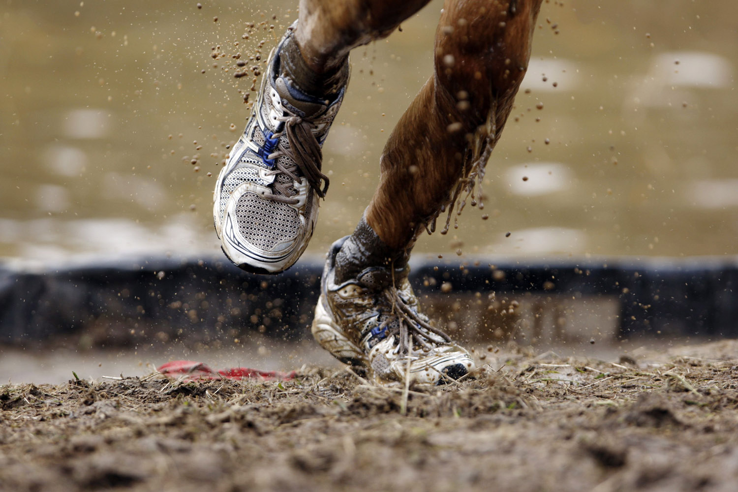 July 15, 2012. Mud flies off a competitor's shoes as he runs out of an obstacle during the Tough Mudder at Mt. Snow in West Dover, Vermont.