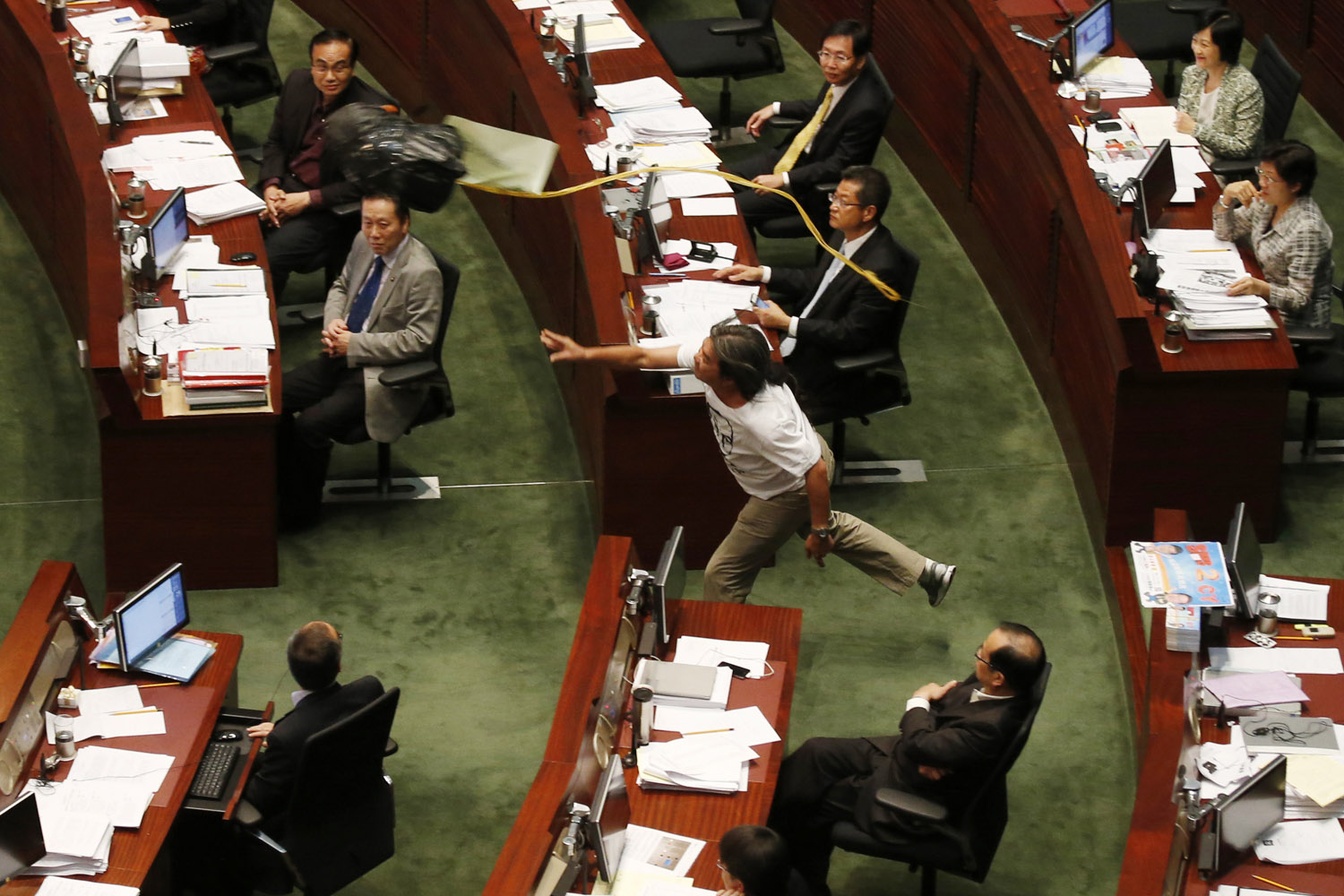July 16, 2012. A member of the Legislative Council Leung Kwok-hung, also known as Long Hair, center, throws an effigy of the head of Chief Executive Leung Chun-ying to Leung during the first question-and-answer session in Hong Kong.