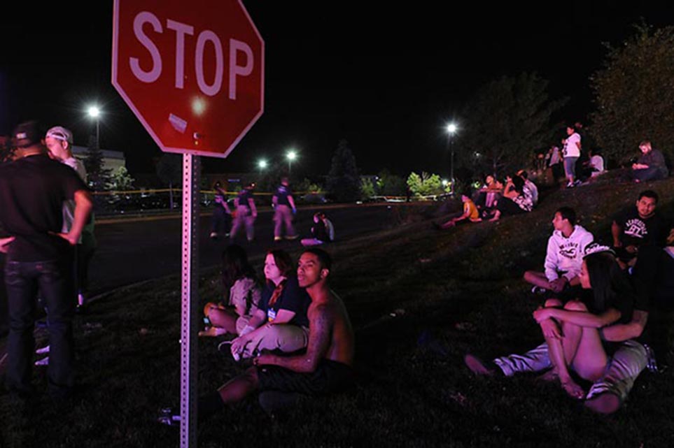 Moviegoers sit outside after being evacuated from the Century 16 movie theater in Aurora, Colo., after a shooting early Friday morning, July 20, 2012.