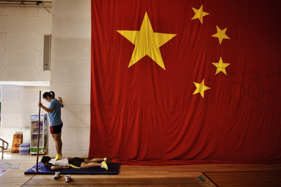 A traditional Chinese massage technique, shown here, in which a trainer walks with sticks on a person's back, is often used on athletes.