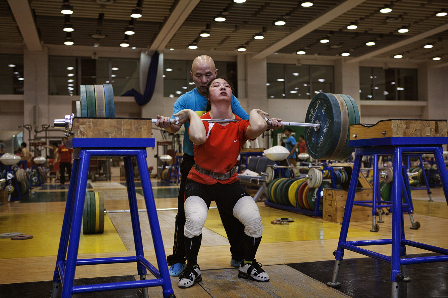 A coach aids a young weight lifter training for the Chinese women's Olympic team at the national sports training center in Beijing.