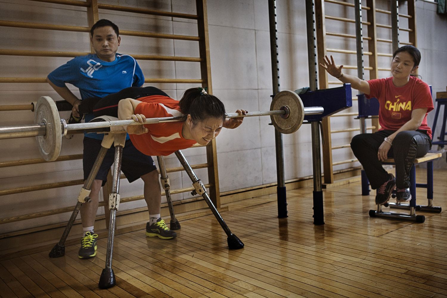 An athlete is spotted by her coach while training for the Chinese women's Olympic weight-lifting team.