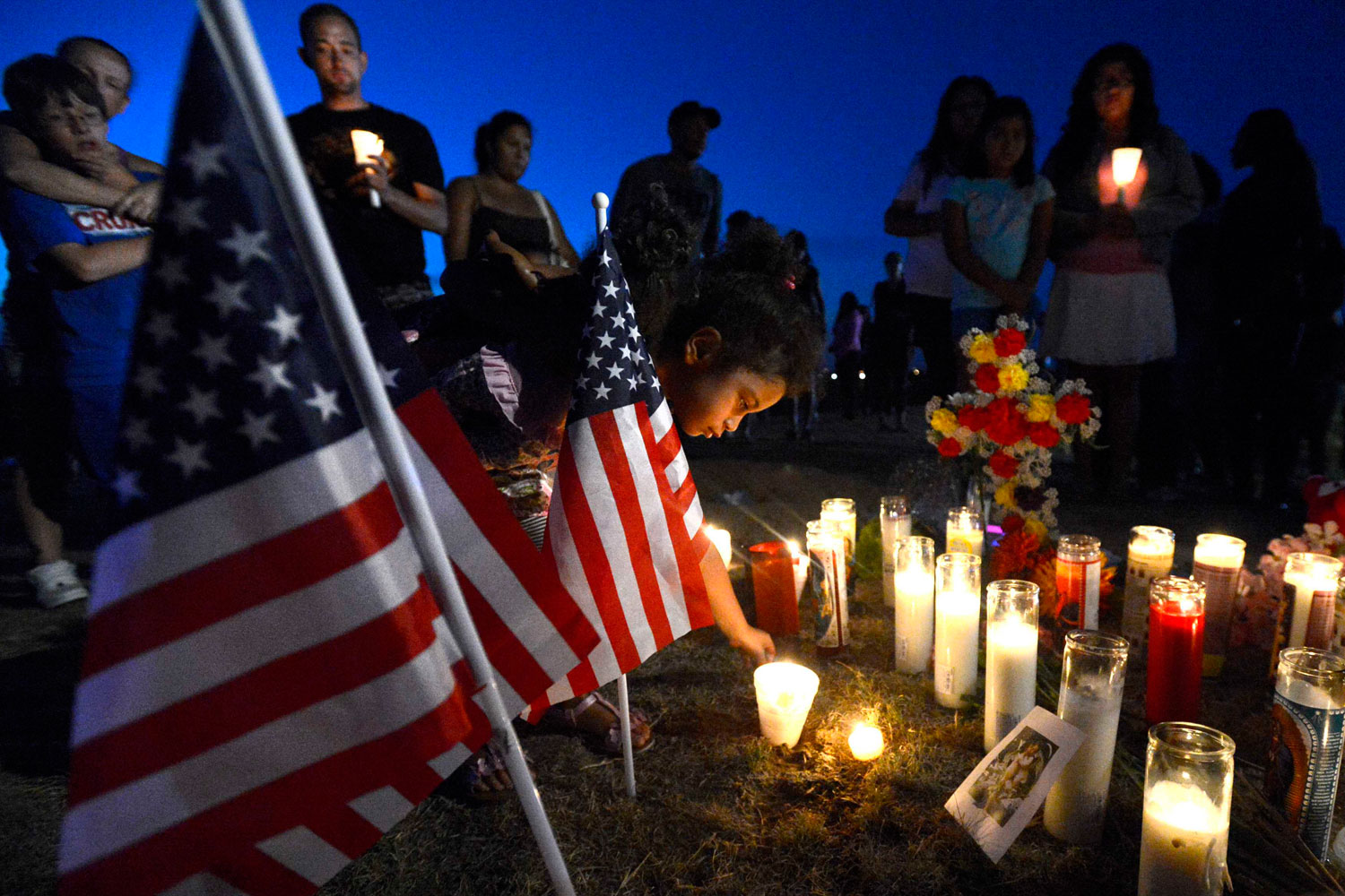 July 20, 2012. Myia Young, 4, places a candle by an American flag during a vigil for victims behind a theater where James Holm opened fire on moviegoers in Aurora, Colo.