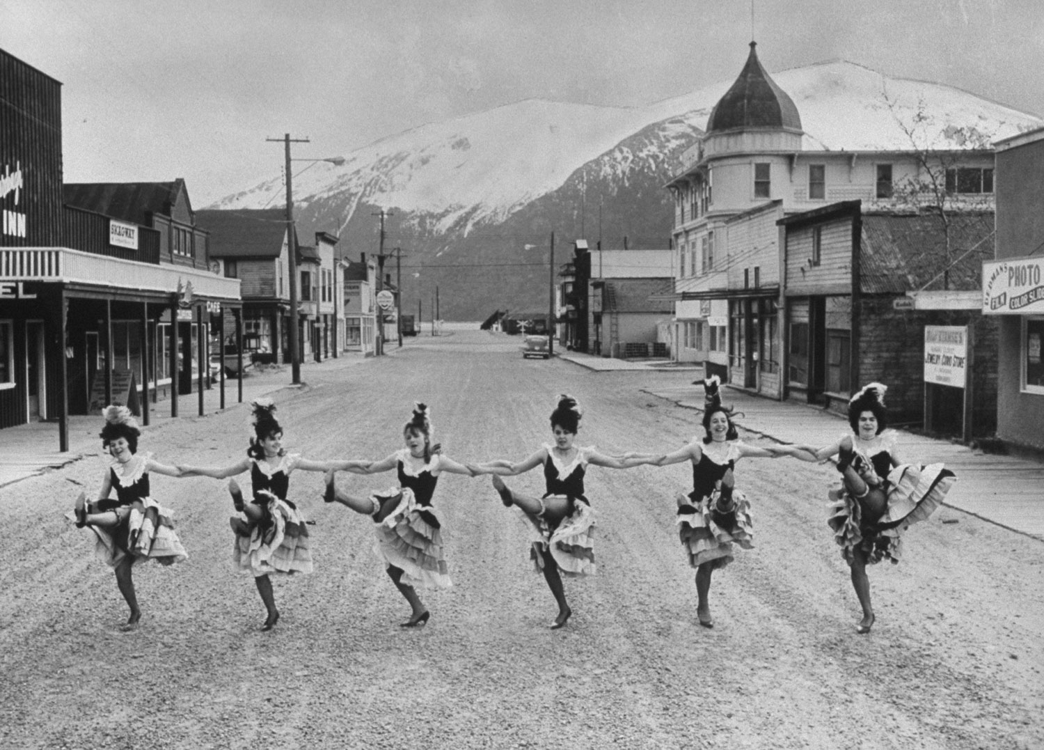 Skagway girls who dance in the Days of '98 show do the cancan in the middle of main street. The domed Golden North Hotel and false-front buildings date back to Klondike gold-rush days.