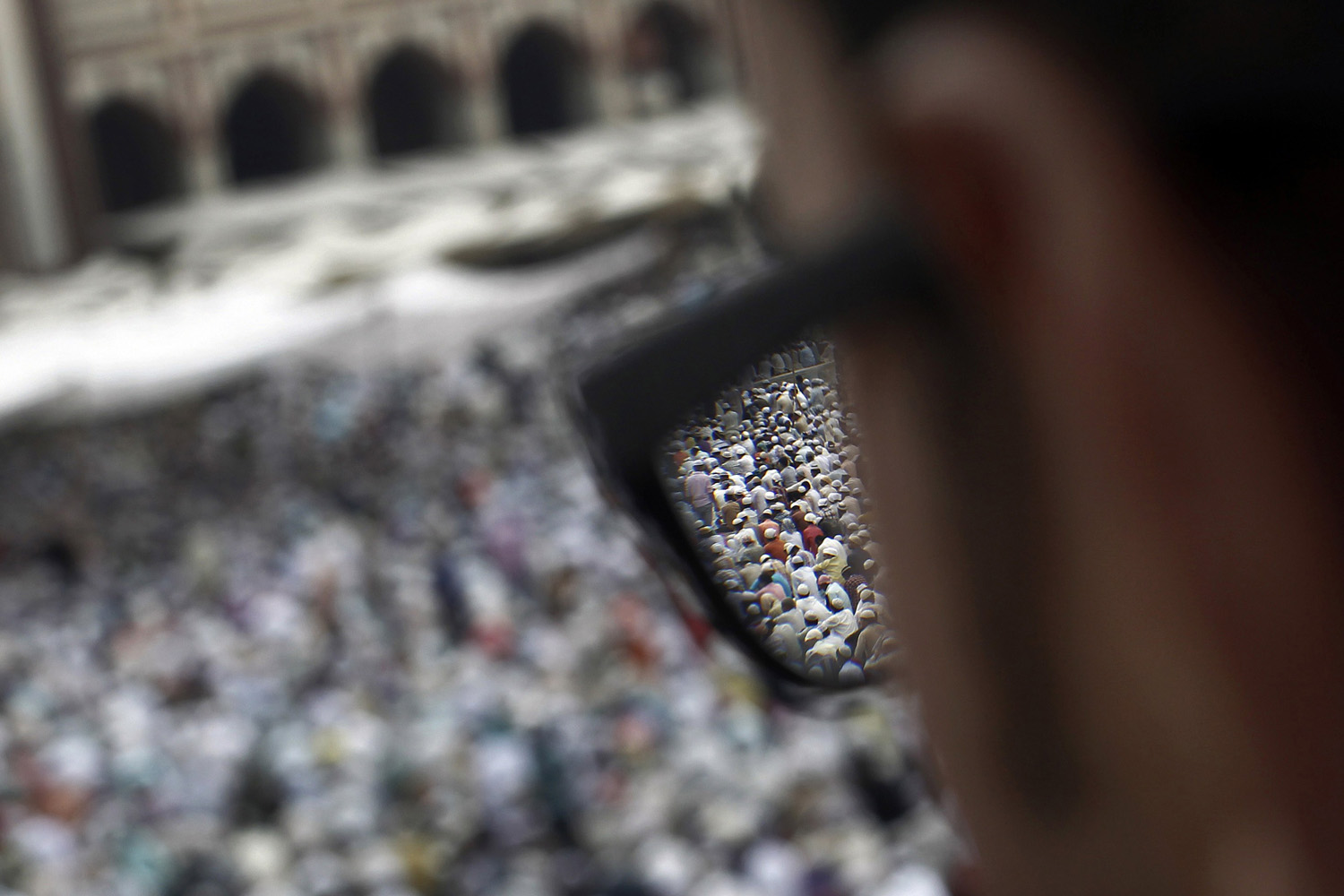 Aug. 17, 2012. Muslims offering last Friday prayers are seen through the spectacles of a man at the Jama Masjid (Grand Mosque) before Eid-al-Fitr in the old quarters of Delhi.