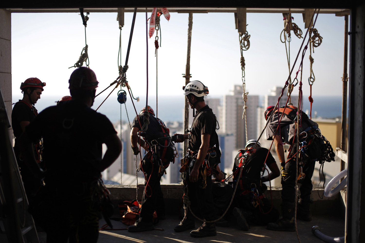 Aug. 20, 2012. Israeli firefighters prepare their gear before rappelling from a building as they take part in a drill with soldiers from the Home Front Command during a simulated missile attack on an apartment block, in the southern city of Ashkelon.